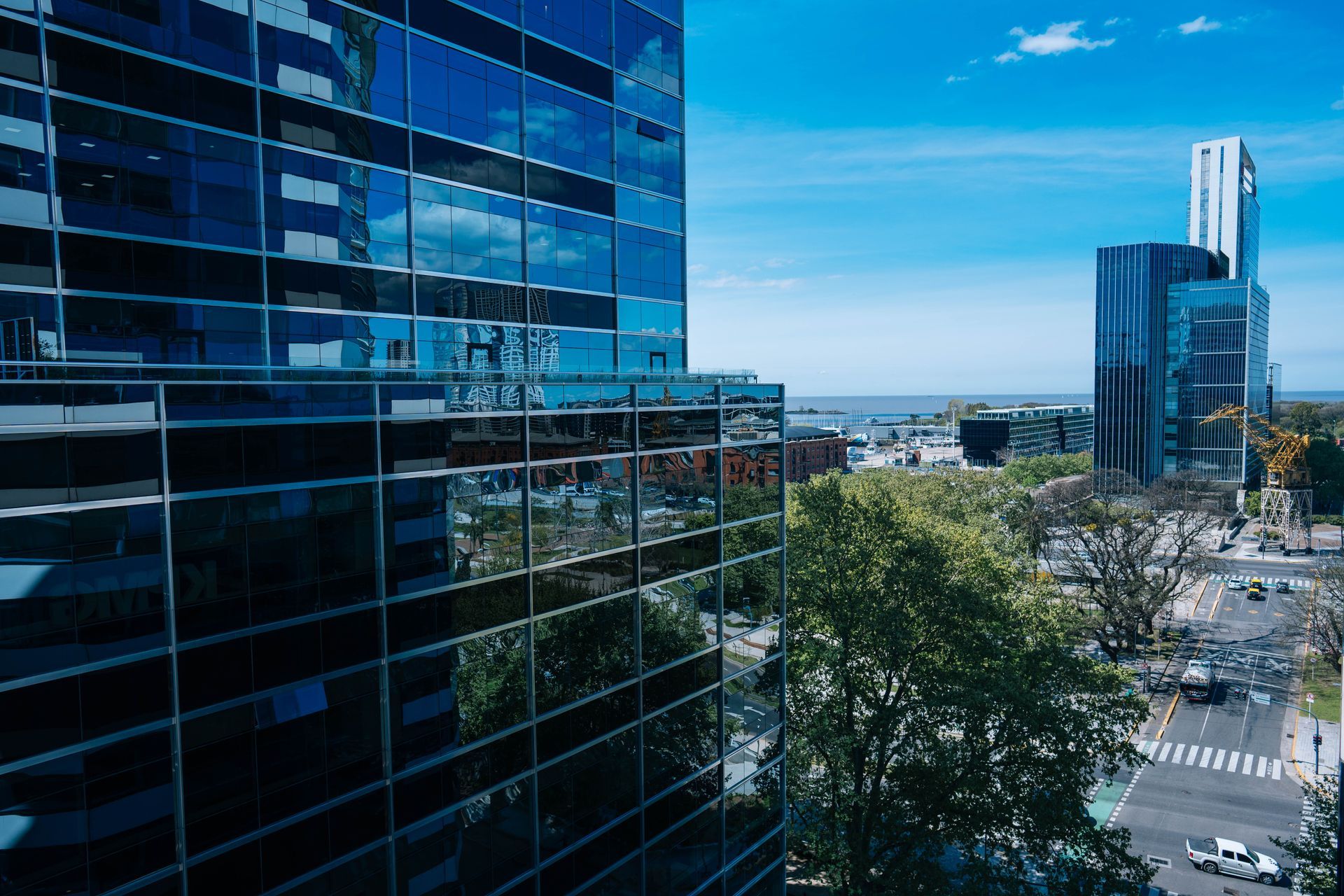 Los rascacielos de cristal reflejan el cielo azul y las vistas de la ciudad. Un día soleado con tráfico abajo.