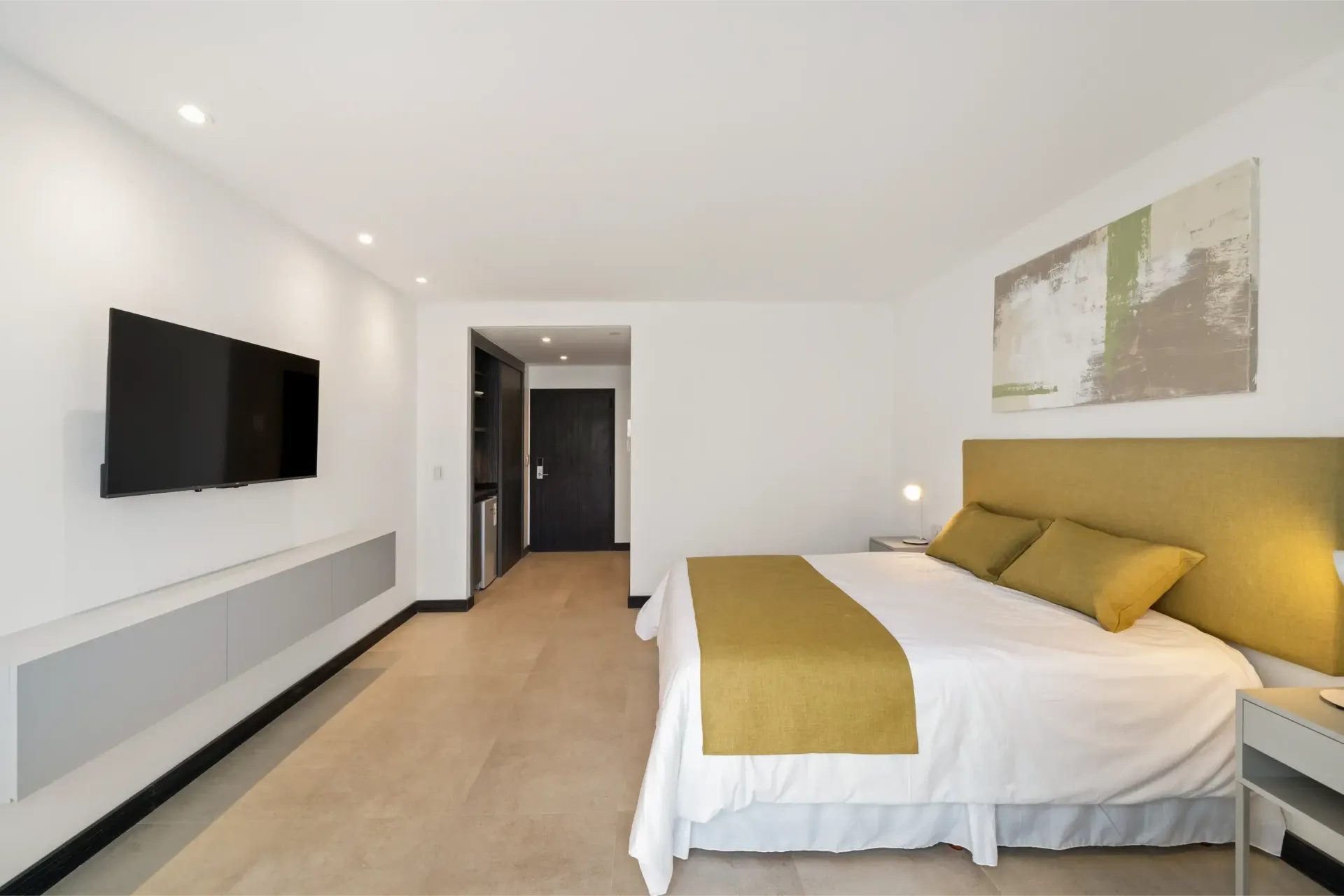 Una habitación de hotel con una cama tamaño king y un televisor de pantalla plana en la pared.