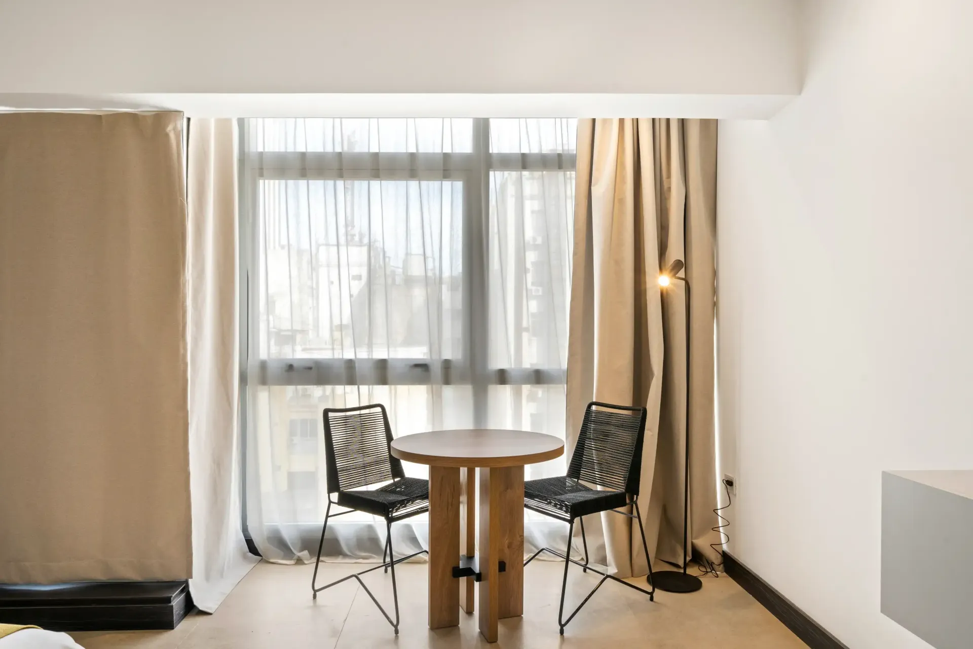 Una habitación con una mesa y sillas frente a una ventana.