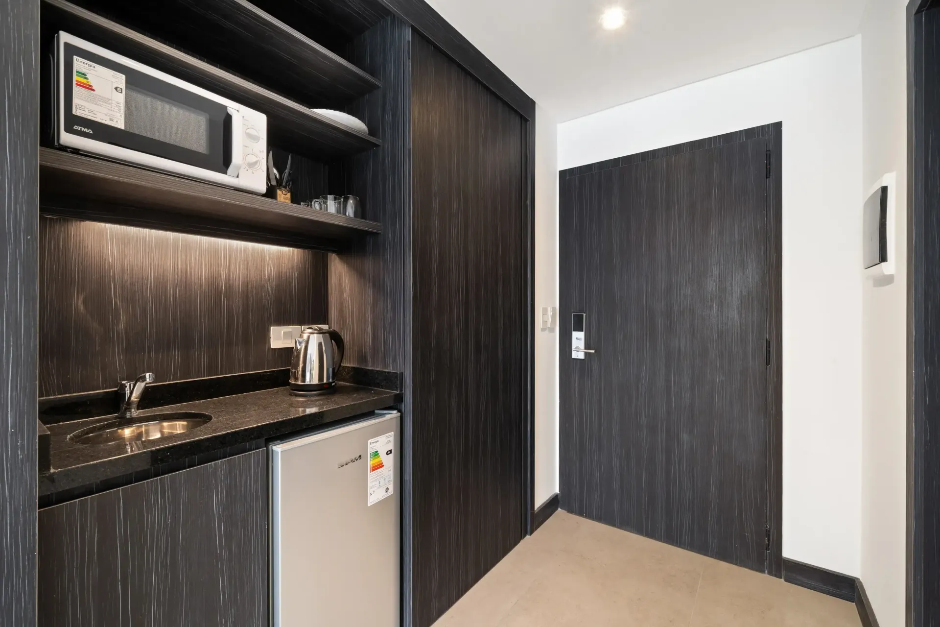 Una cocina en una habitación de hotel con microondas, fregadero y refrigerador.