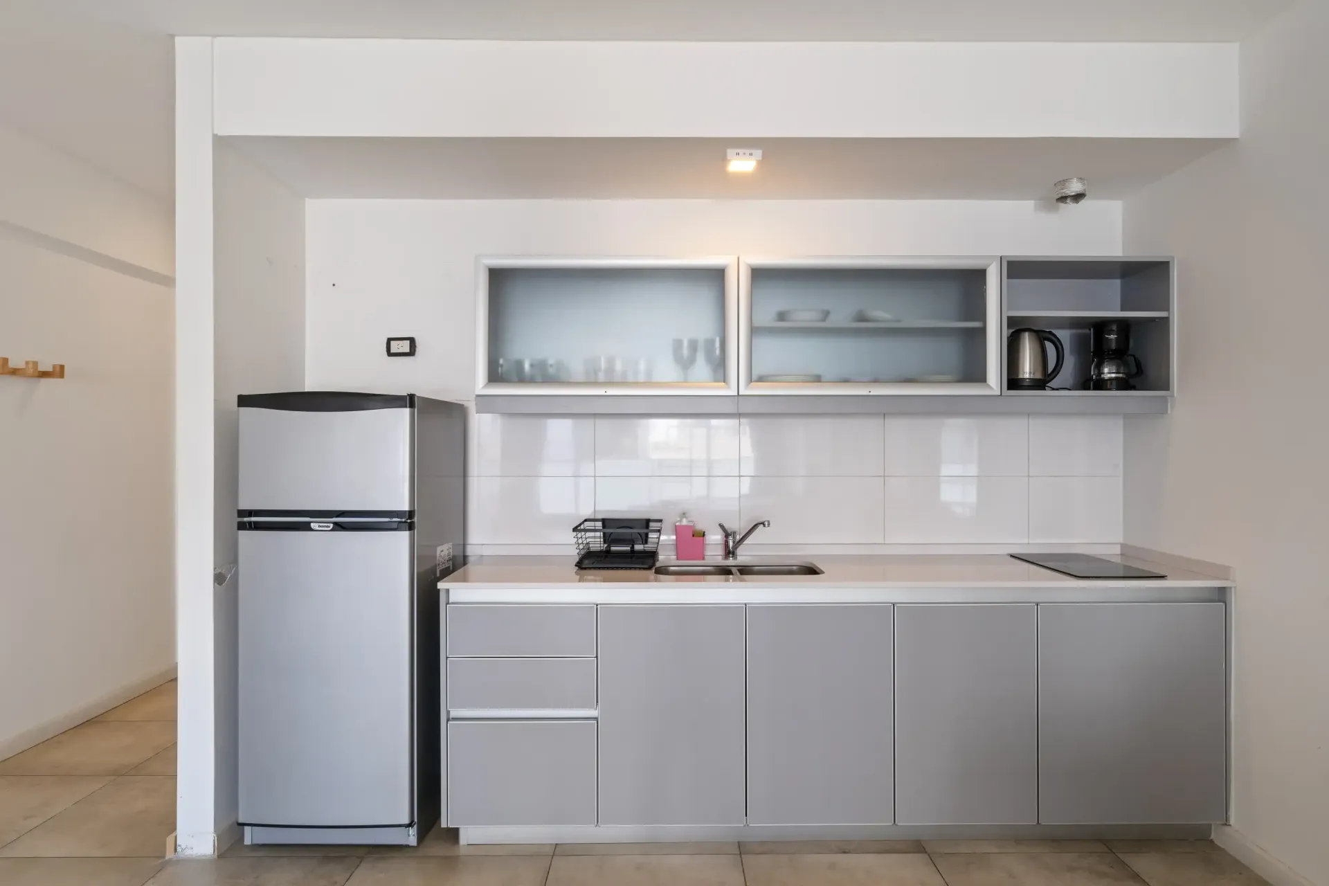 Una cocina con gabinetes grises y un refrigerador plateado.
