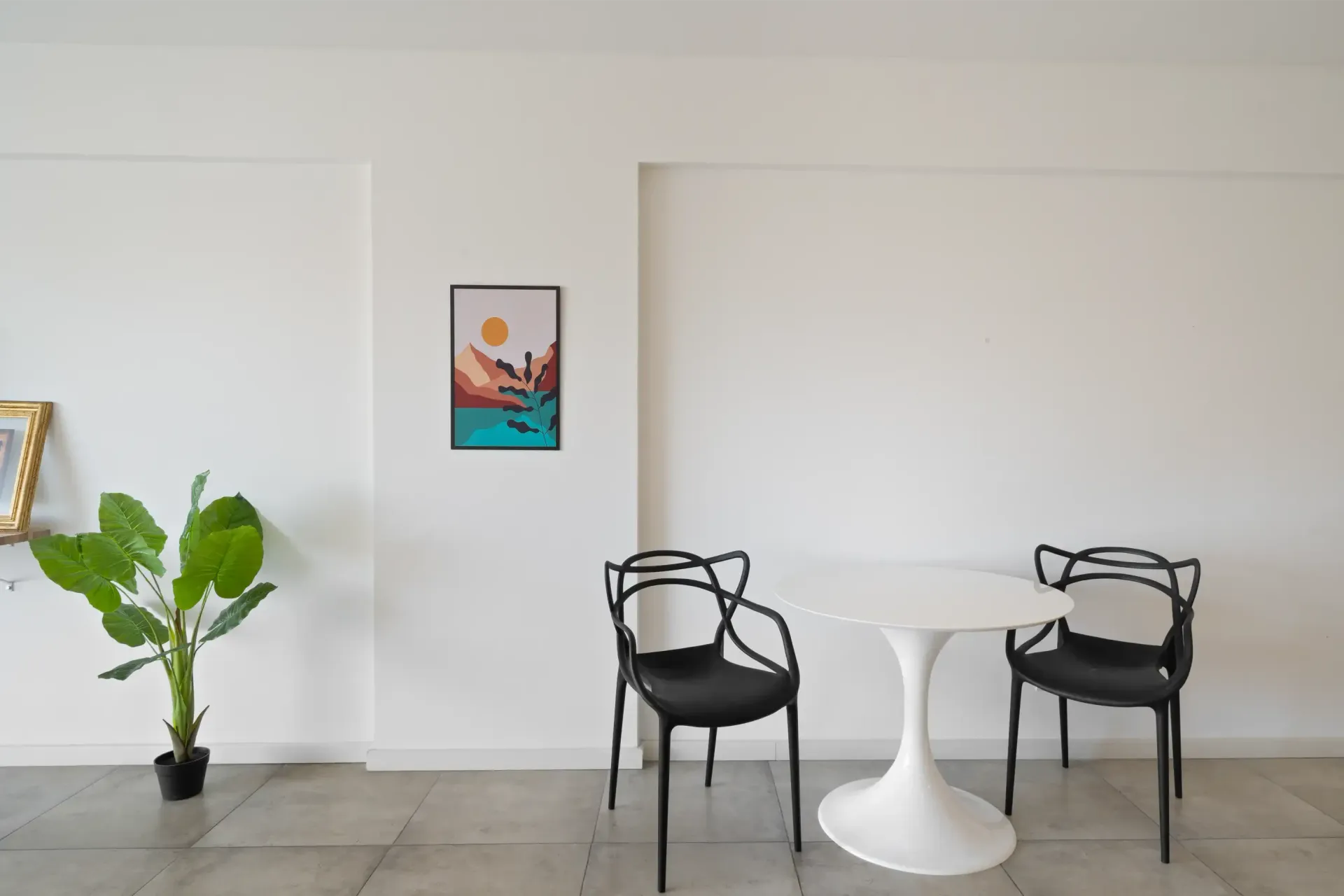 Hay una mesa y sillas en la habitación con un cuadro en la pared.