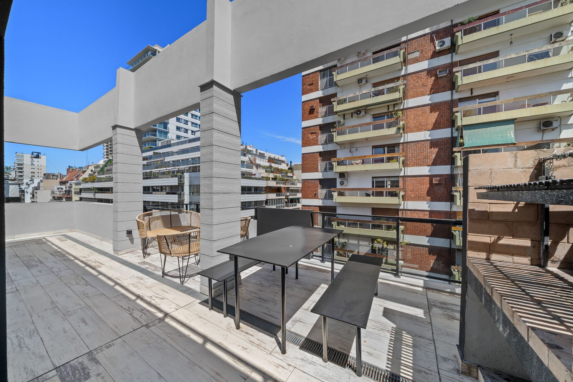 Un balcón con una mesa y sillas frente a un edificio.