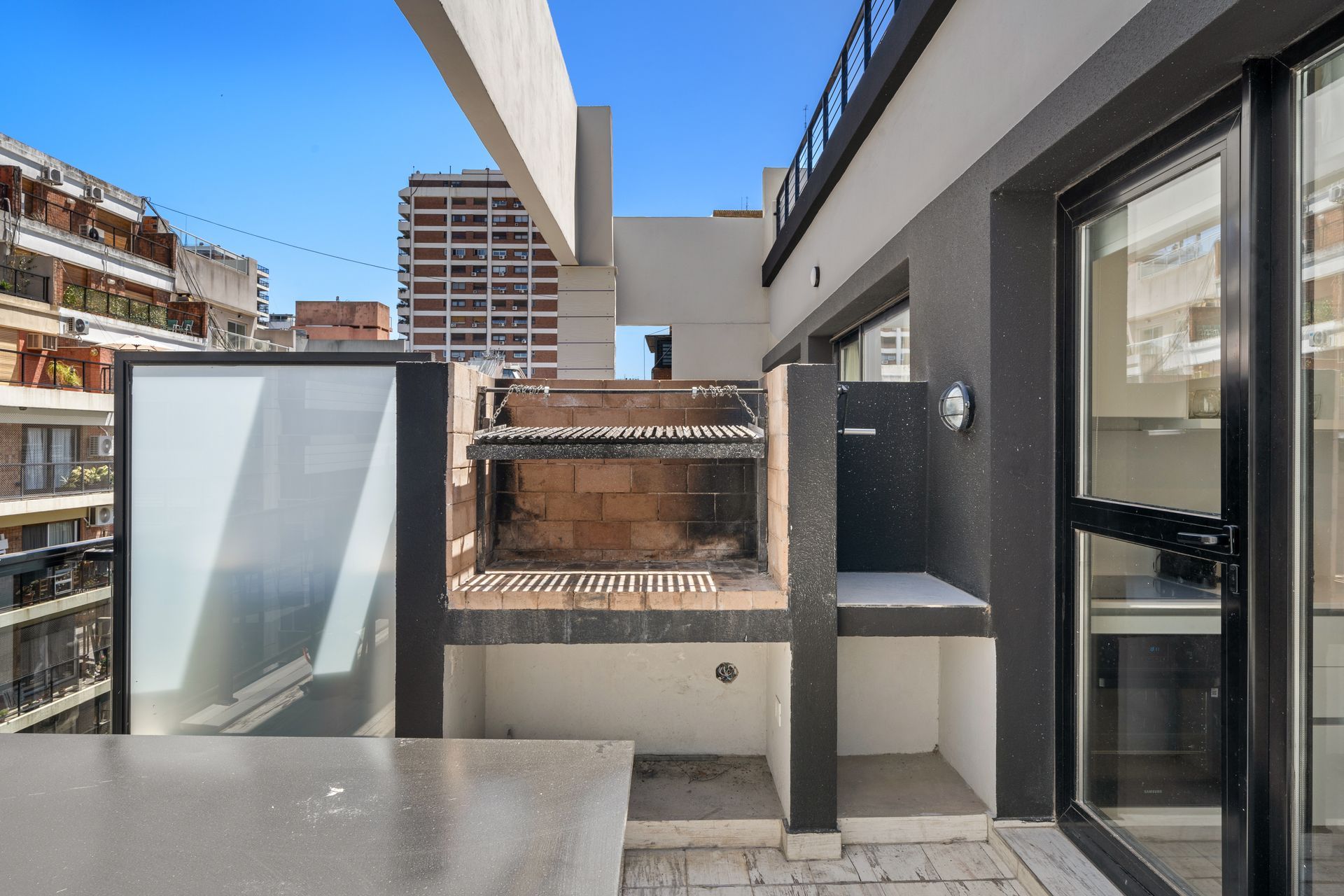 Un balcón con parrilla y puerta corrediza de vidrio.