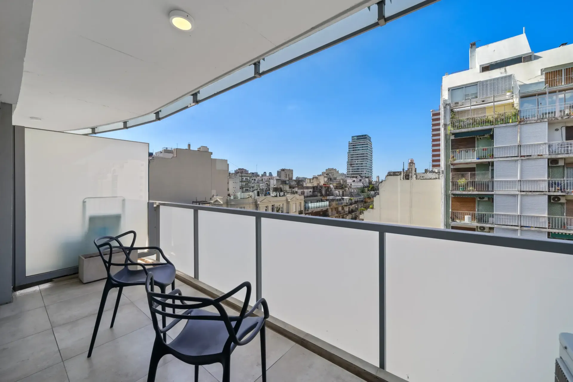 Un balcón con dos sillas y una mesa con vistas a una ciudad.