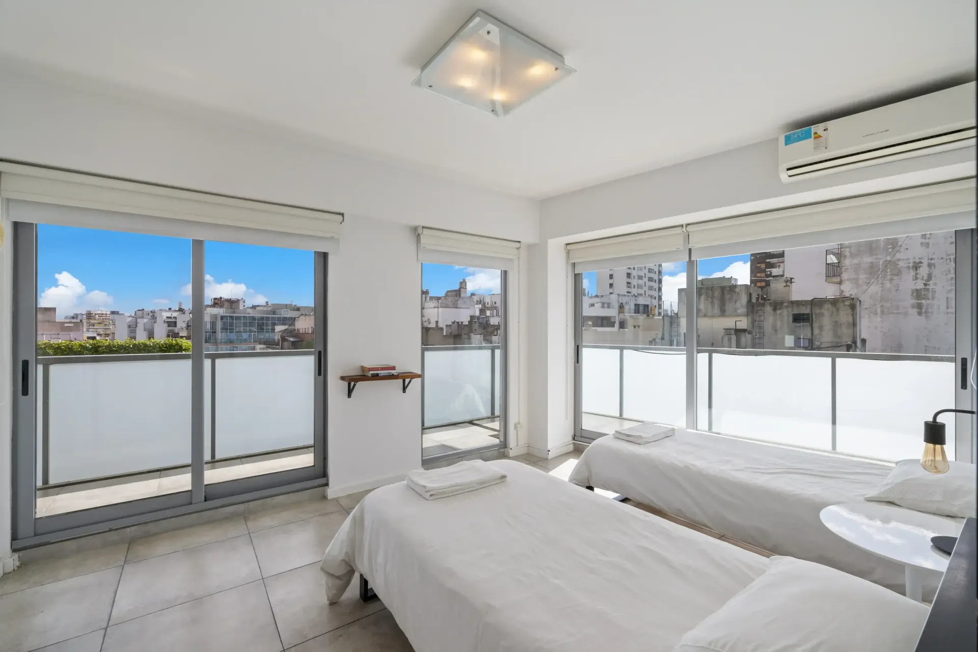 Un dormitorio con dos camas y un balcón con vista a la ciudad.