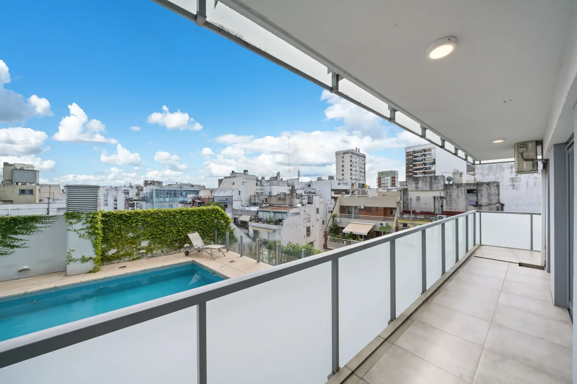 Un balcón con vista a la ciudad y a la piscina.