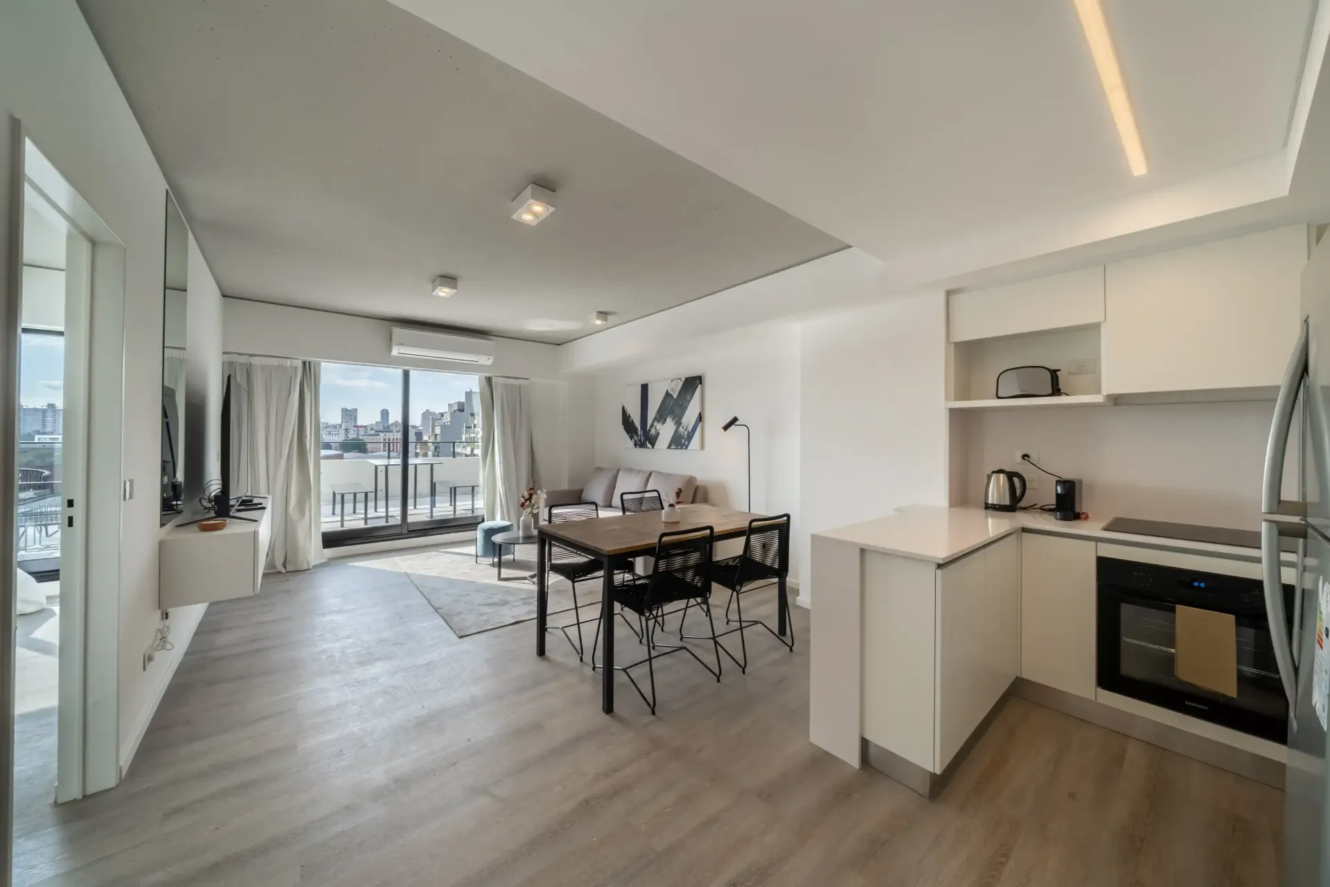 Una sala de estar con una mesa y sillas y una cocina.