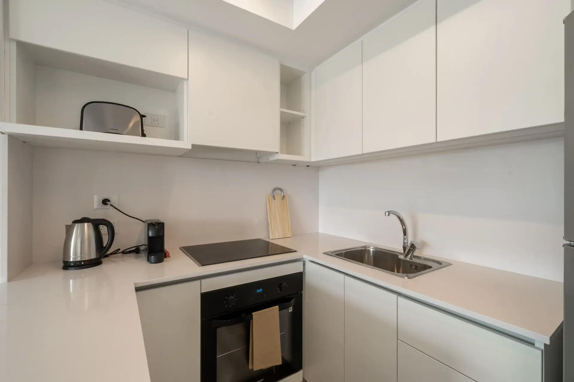 Una cocina con gabinetes blancos, un horno de estufa, un fregadero y un horno tostador.