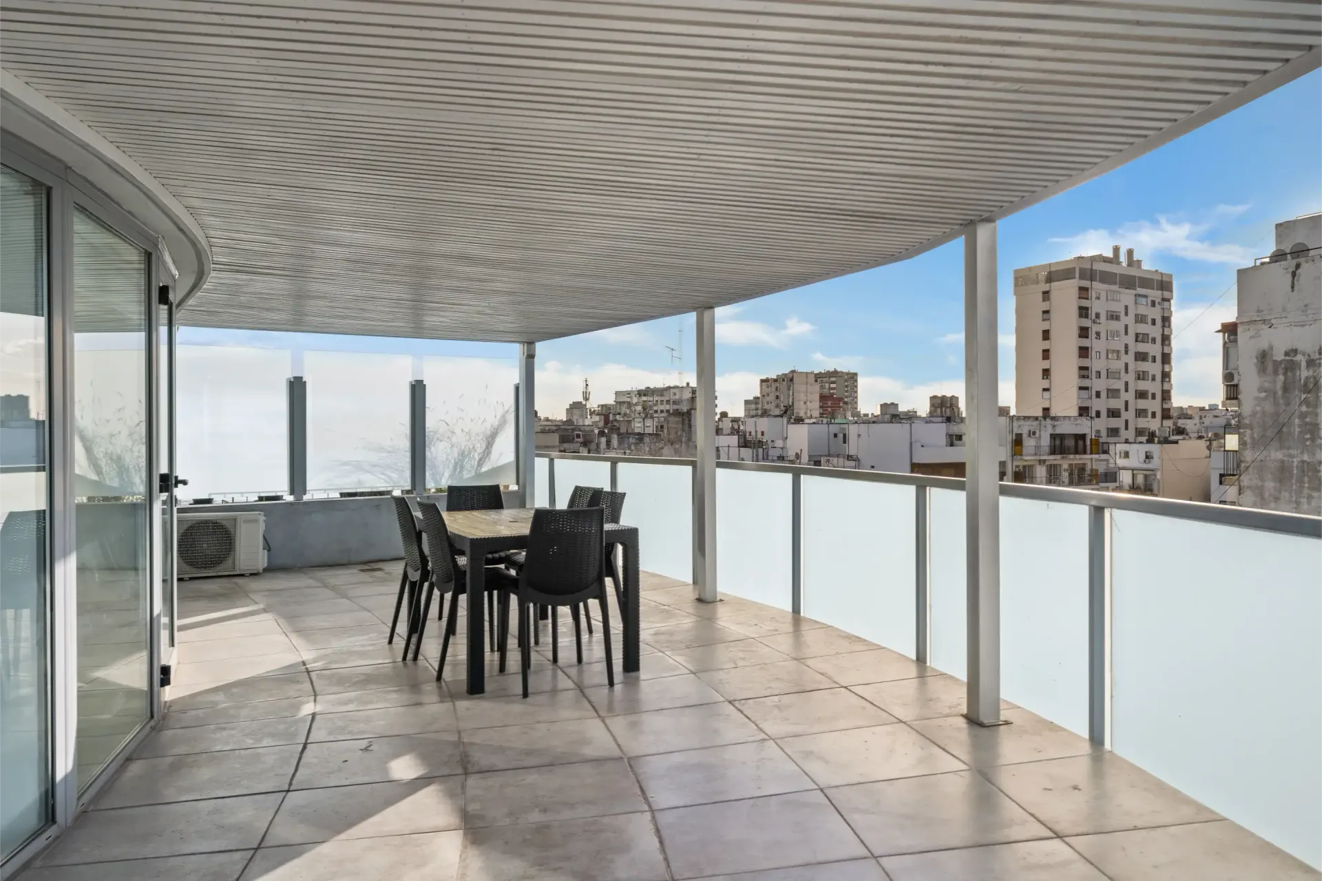 Un balcón con mesa y sillas y vista a la ciudad.