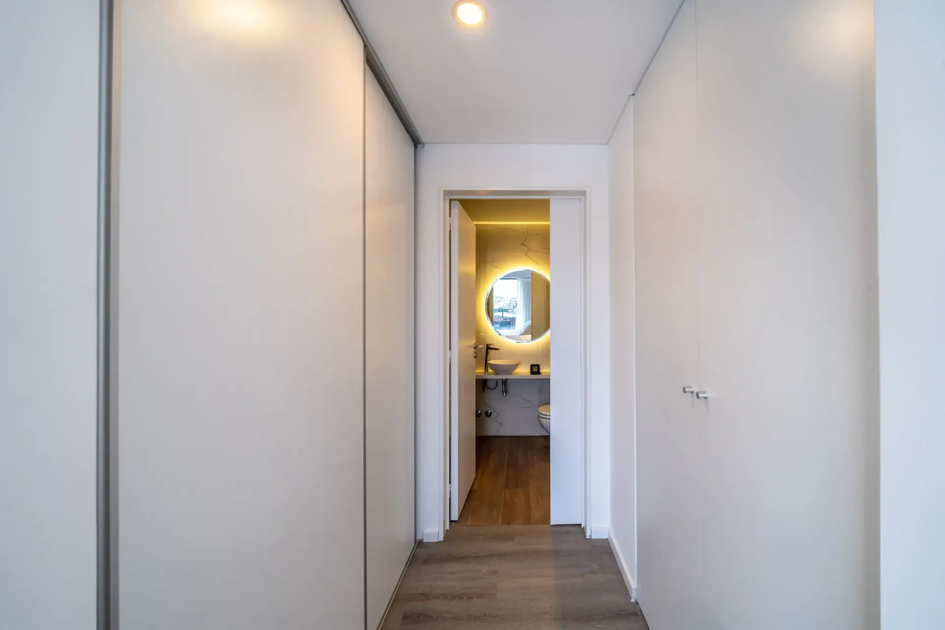 Un pasillo que conduce a un baño con lavabo y espejo.