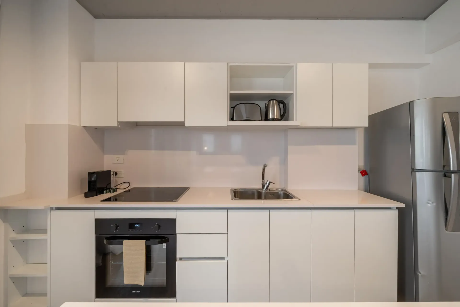 Una cocina con gabinetes blancos y un refrigerador de acero inoxidable.