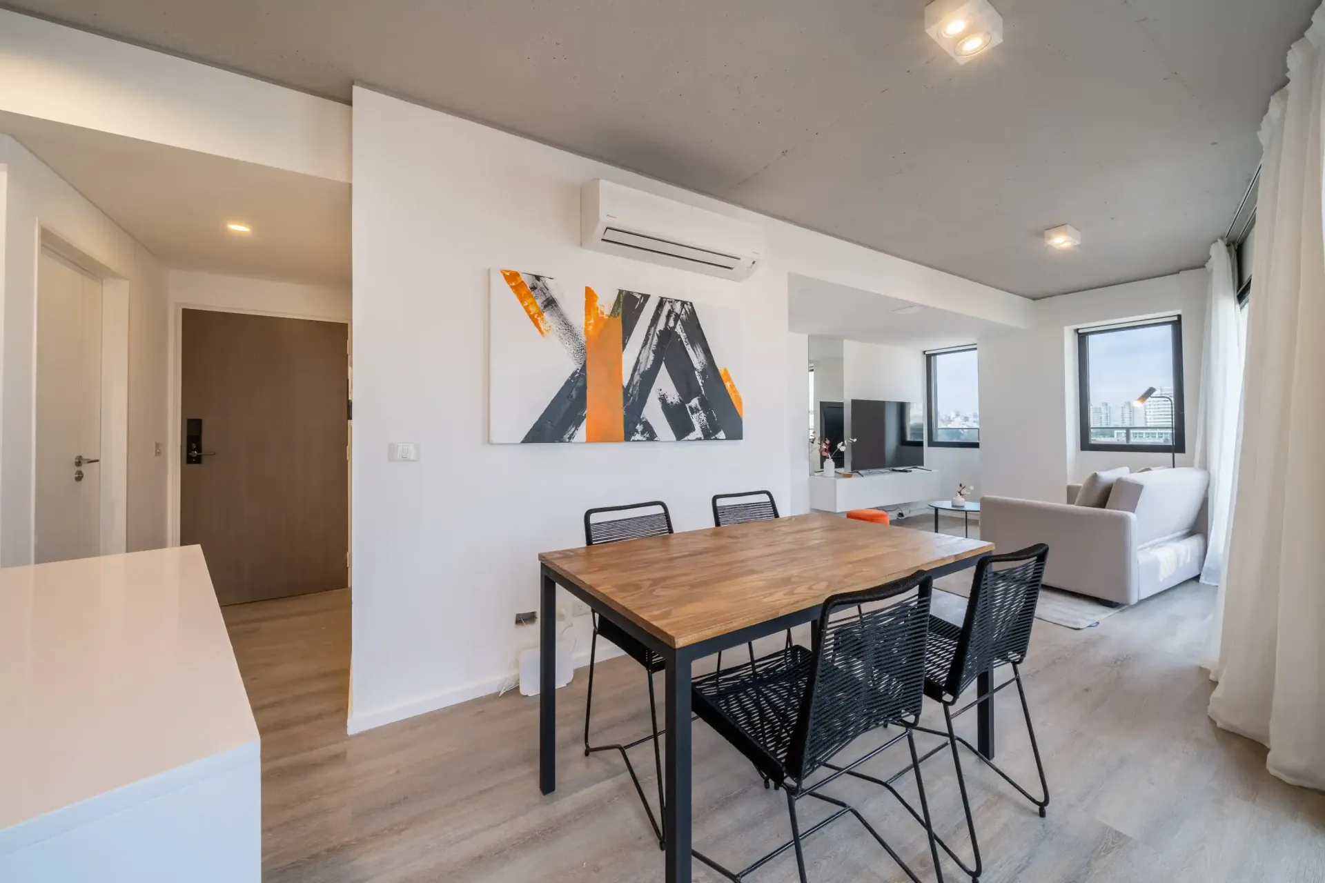Una sala de estar con una mesa de comedor y sillas y un cuadro en la pared.