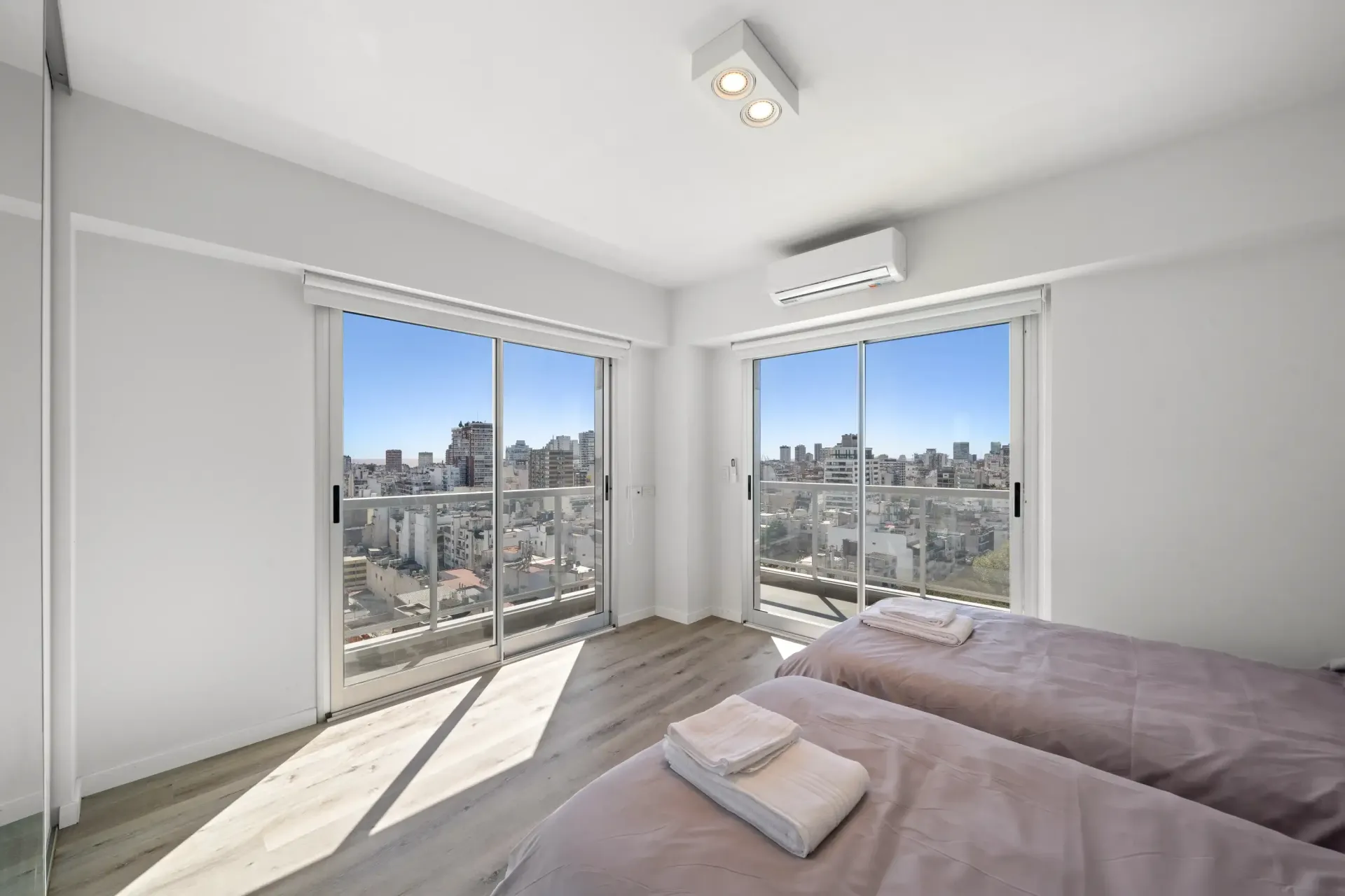 Un dormitorio con dos camas y un gran ventanal con vista a la ciudad.