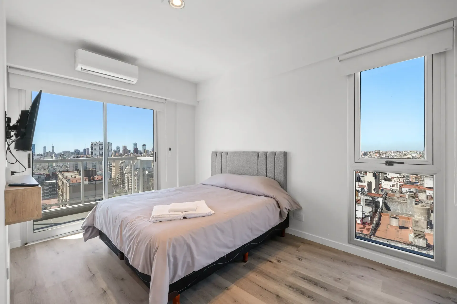Un dormitorio con una cama y una ventana con vista a la ciudad.