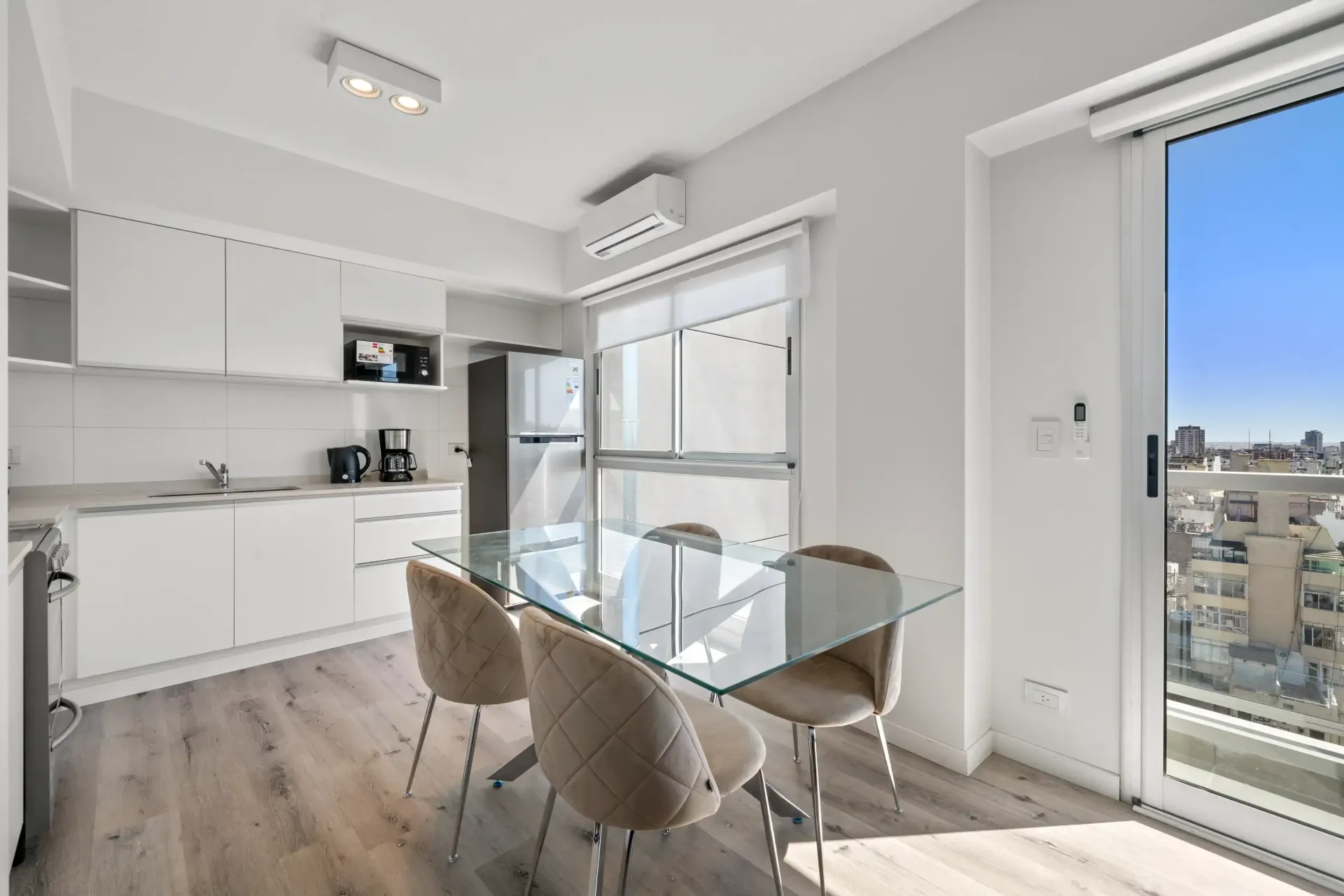Una cocina con una mesa y sillas de cristal y una gran ventana.
