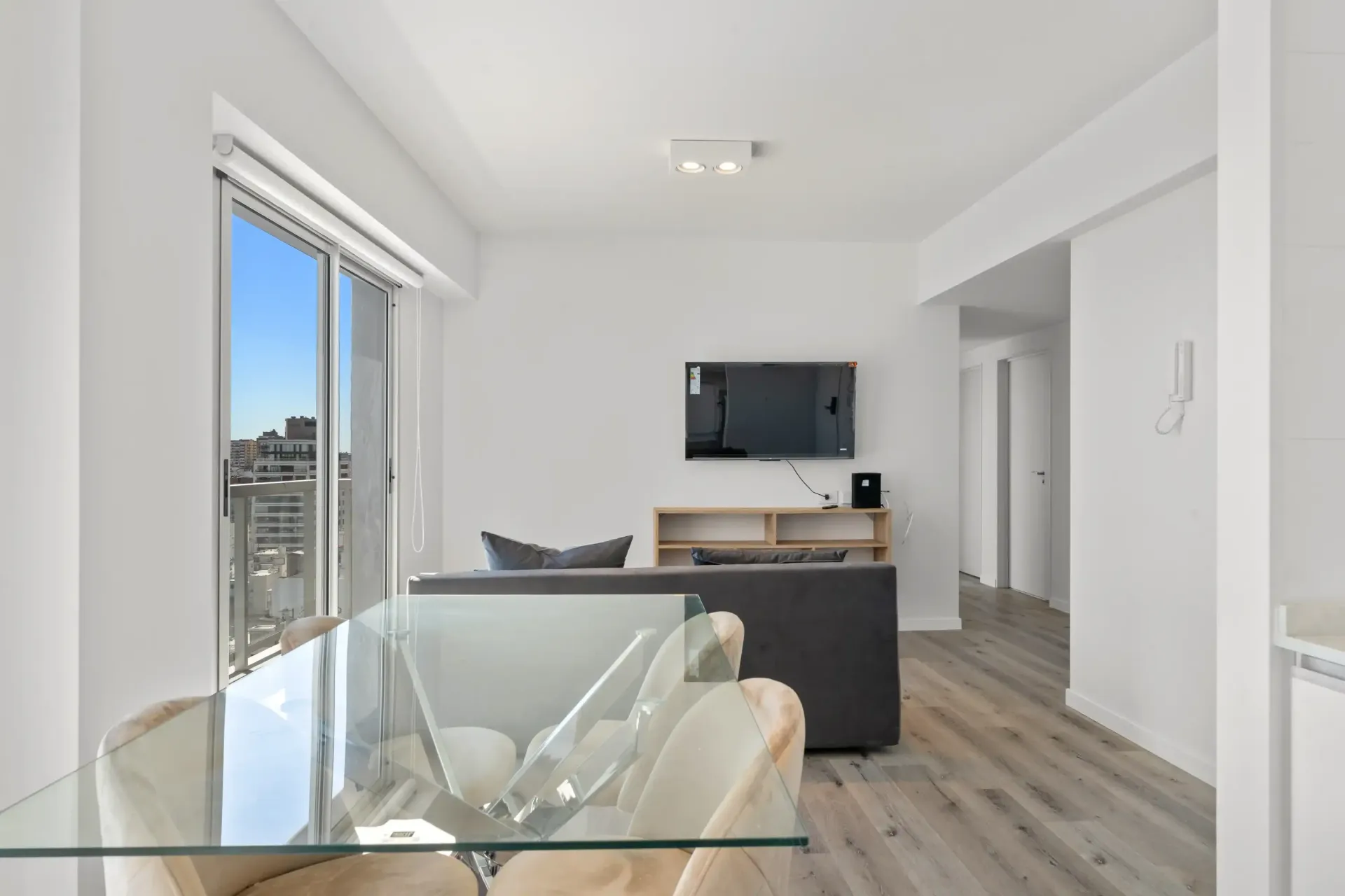 Una sala de estar con una mesa de cristal y sillas y un televisor de pantalla plana en la pared.
