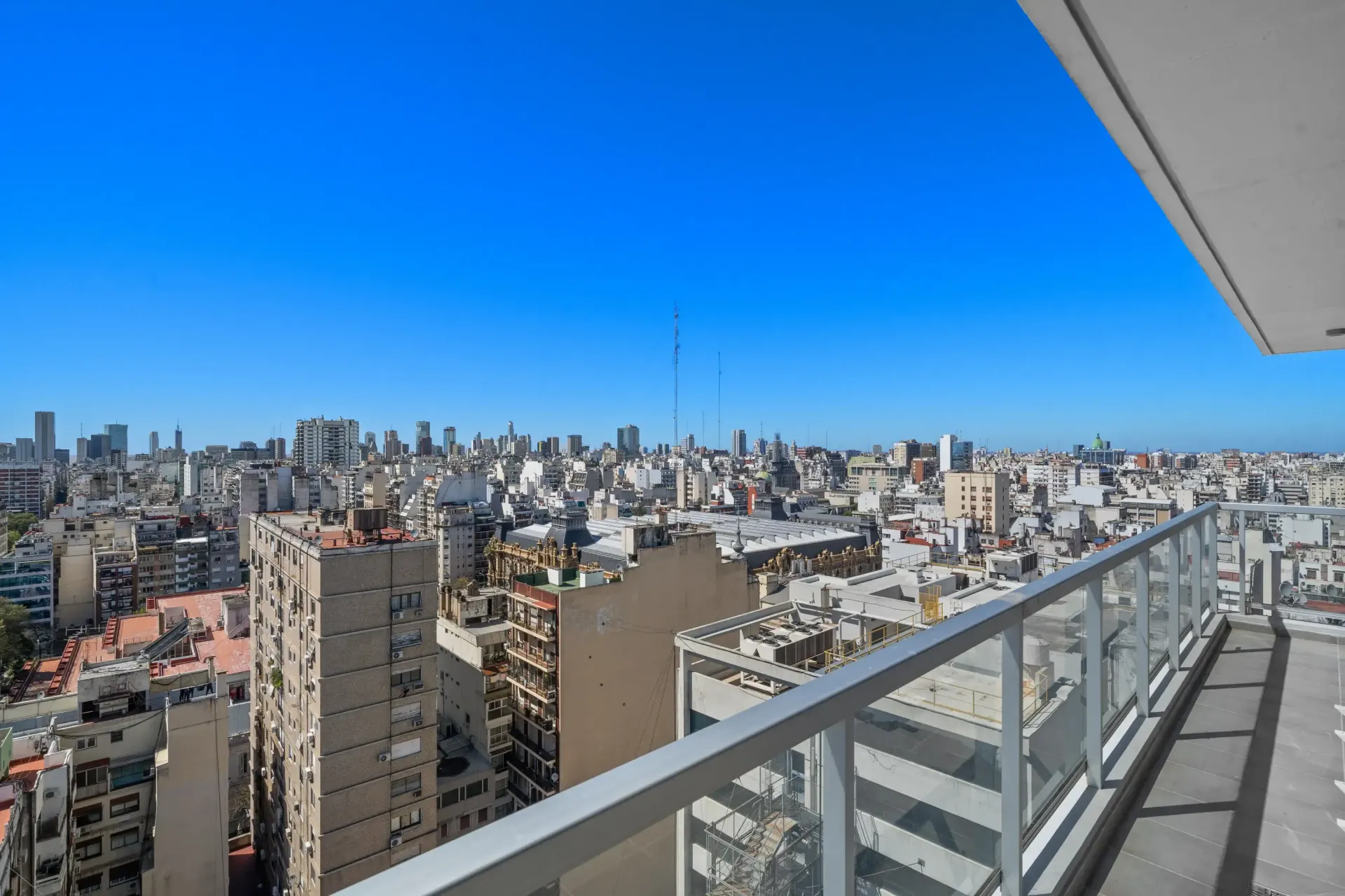 Un balcón con vista a una ciudad con edificios y un cielo azul.