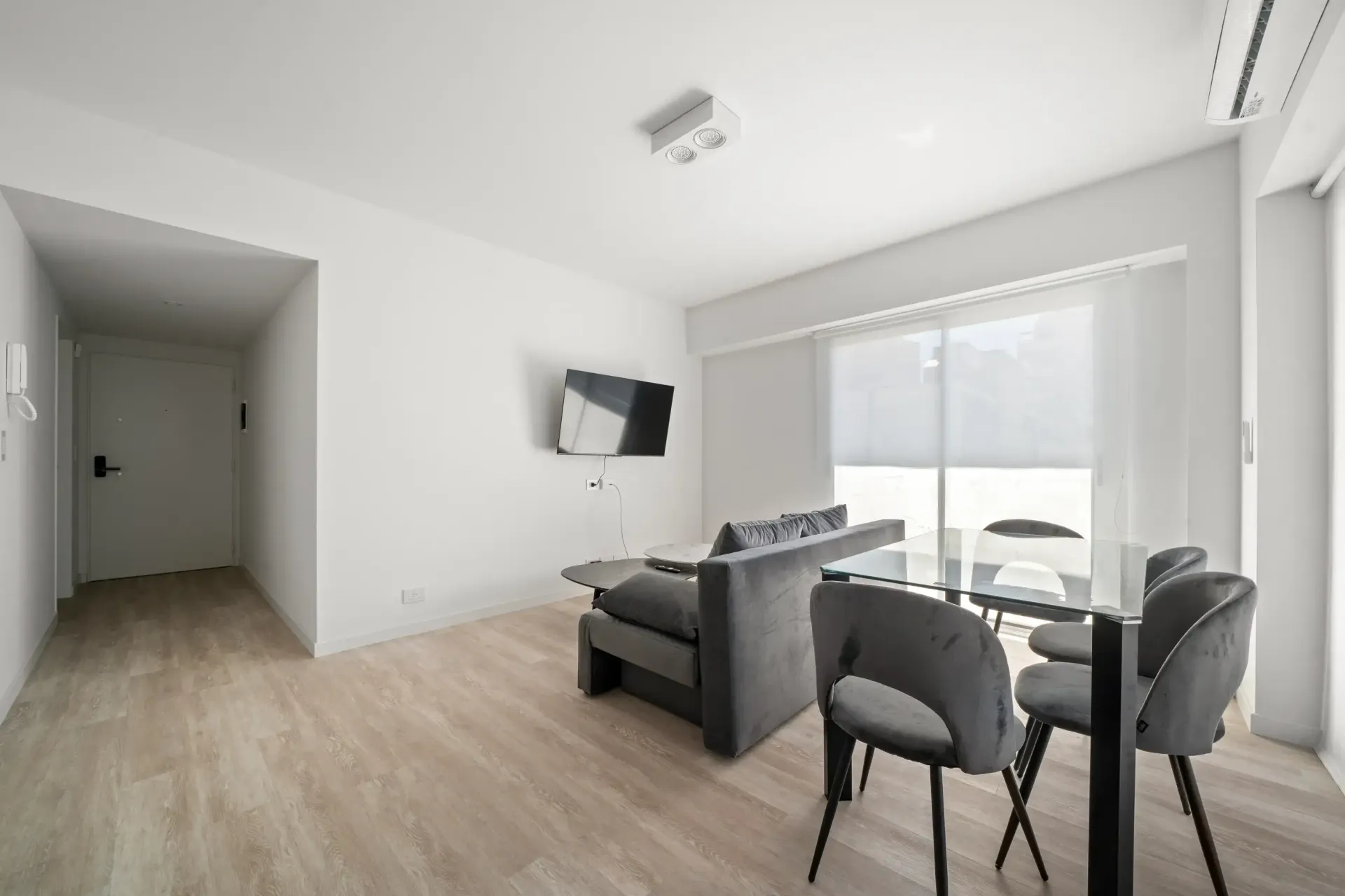 Una sala de estar con un sofá, sillas, una mesa y una televisión.
