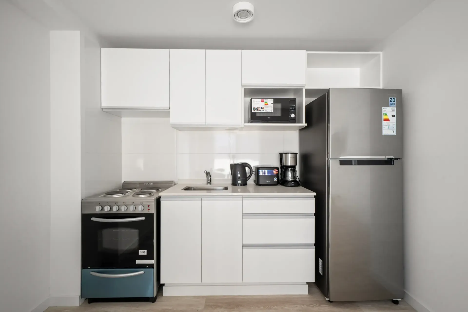 Una cocina con gabinetes blancos y un refrigerador de acero inoxidable.