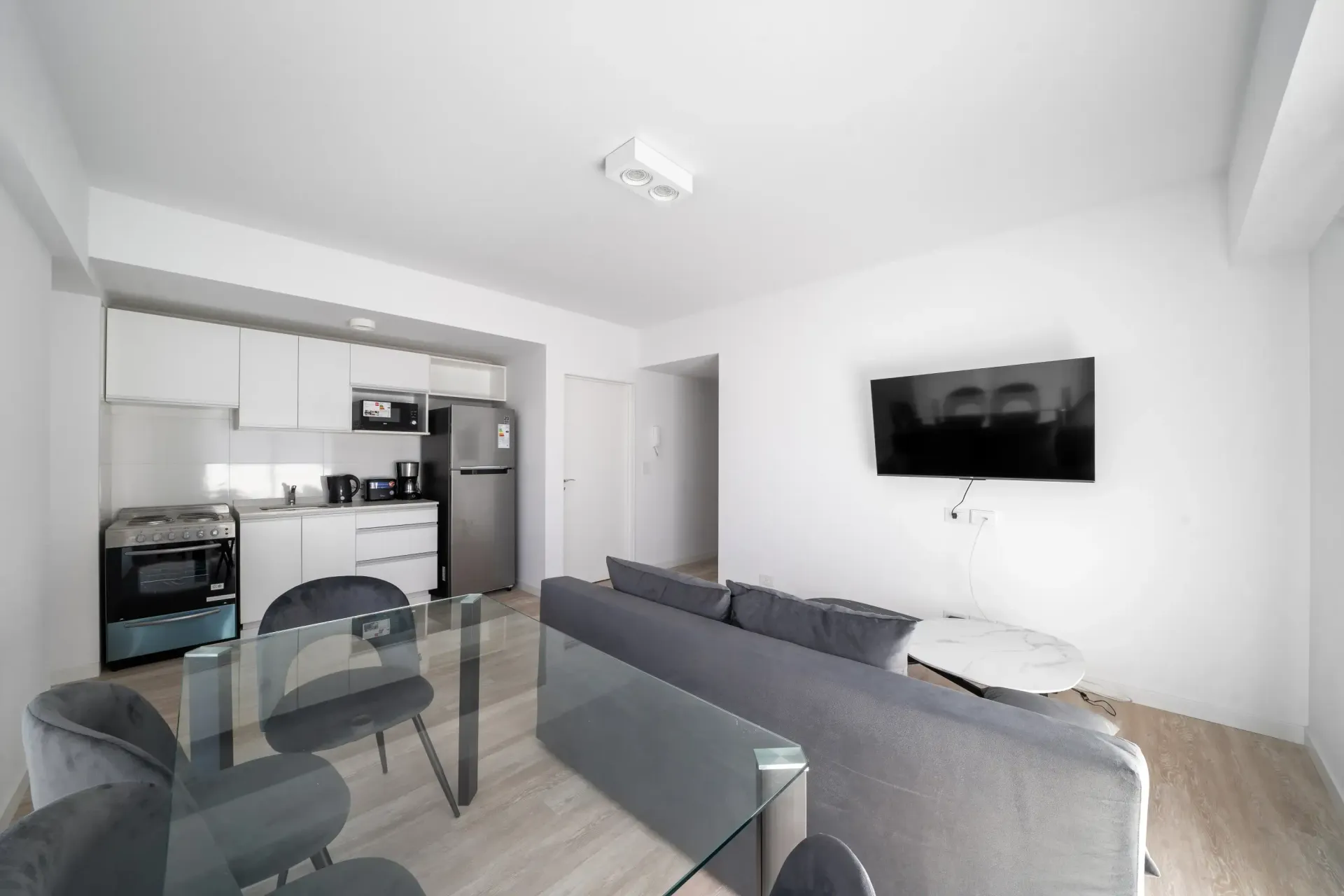 Una sala de estar con sofá, mesa, sillas y televisor de pantalla plana.