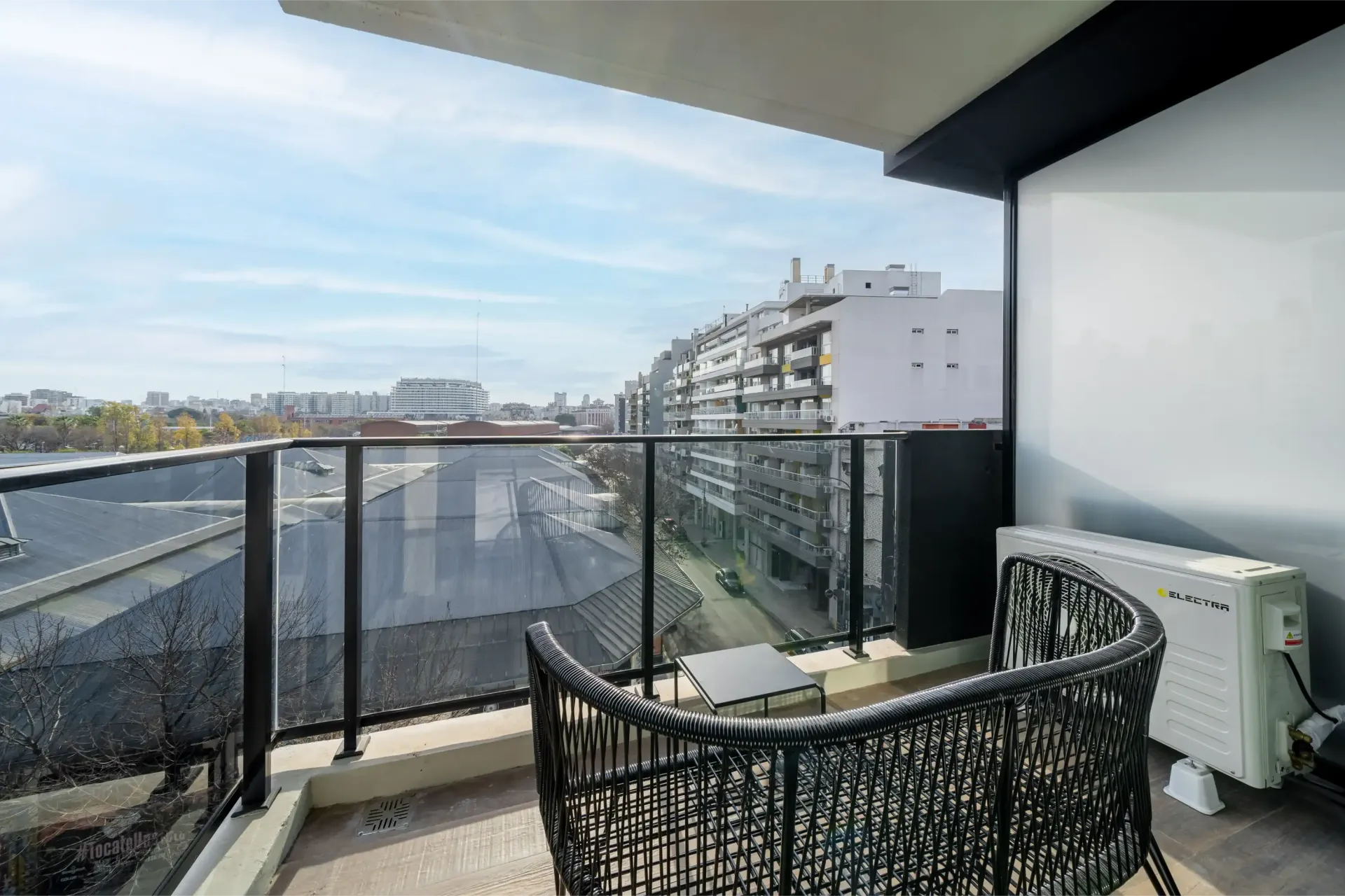 Un balcón con una silla de mimbre y una vista de una ciudad.