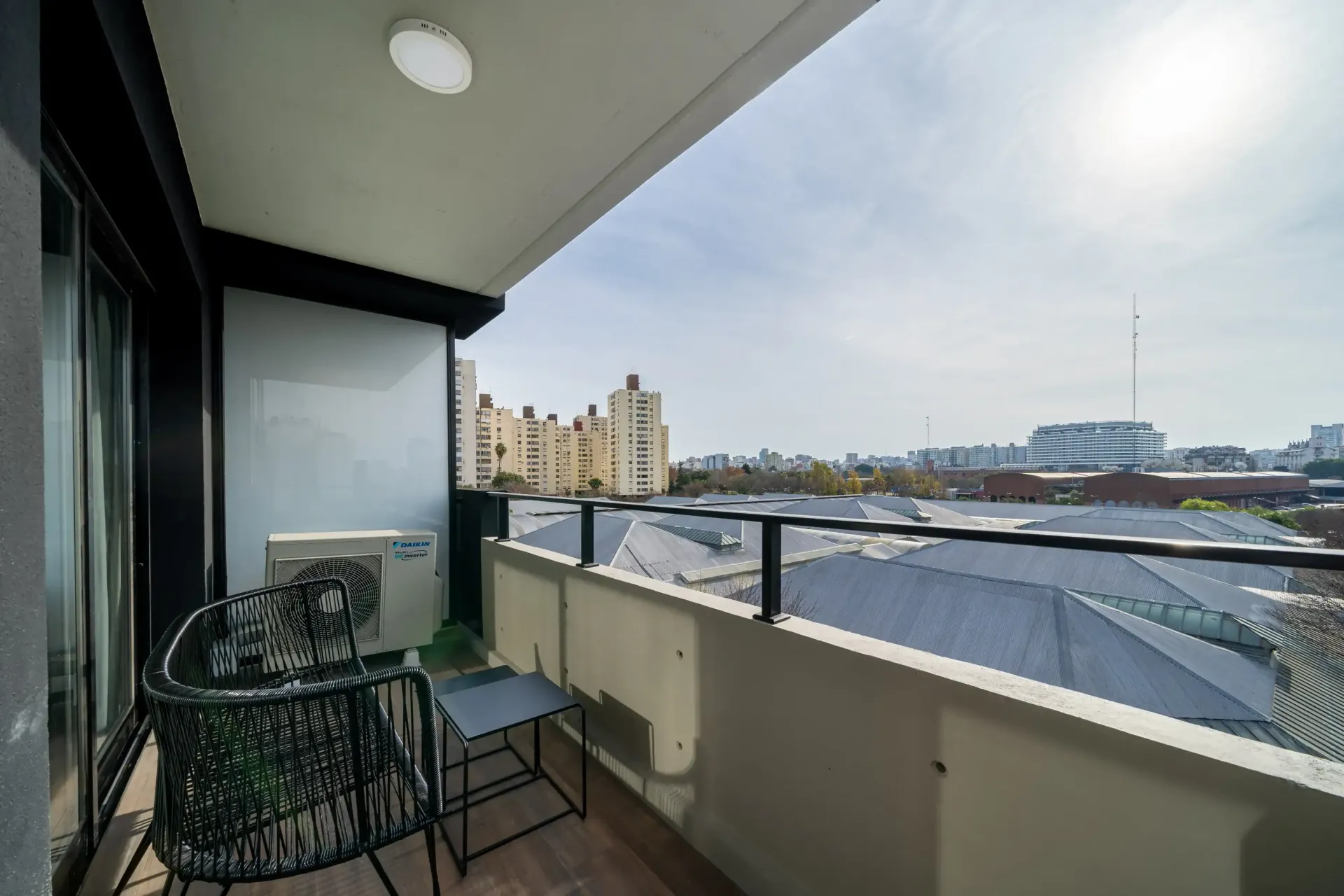 Un balcón con una silla y una mesa con vista a una ciudad.