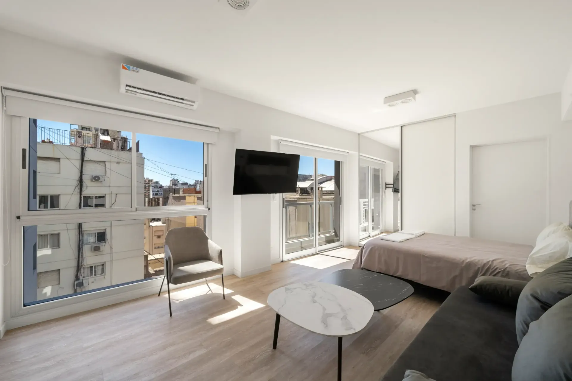 Una sala de estar con cama, sofá, mesa de café y televisión.