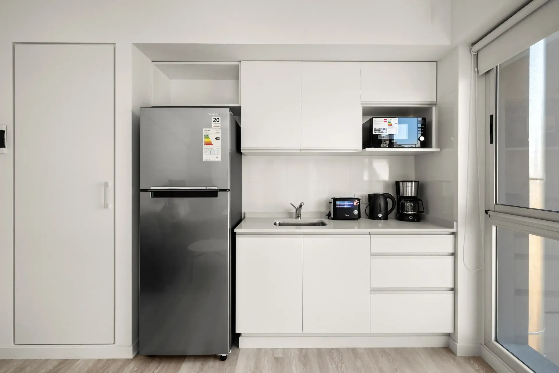 Una cocina con refrigerador de acero inoxidable y gabinetes blancos.