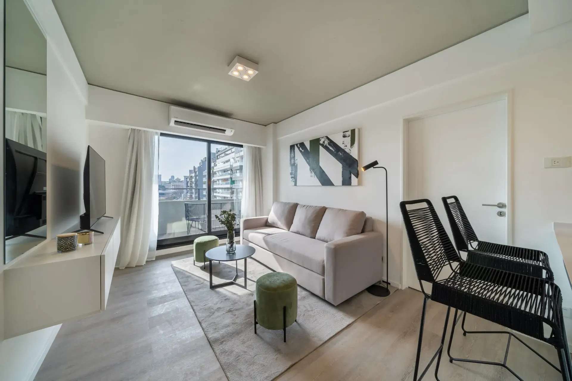 Una sala de estar con un sofá, una mesa, sillas y una televisión.