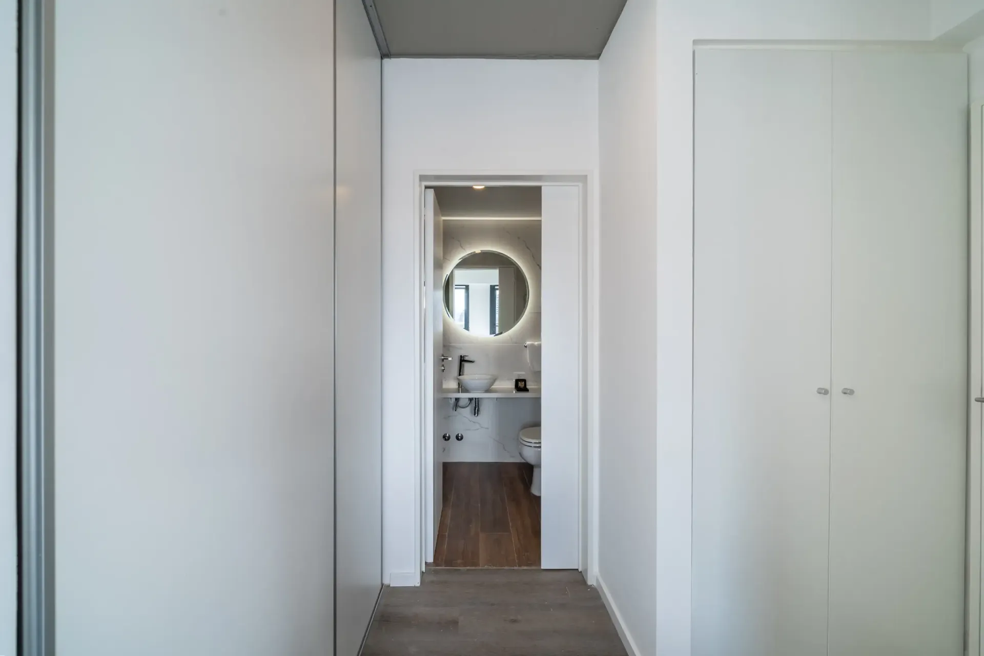 Un pasillo que conduce a un baño con un espejo en la pared.