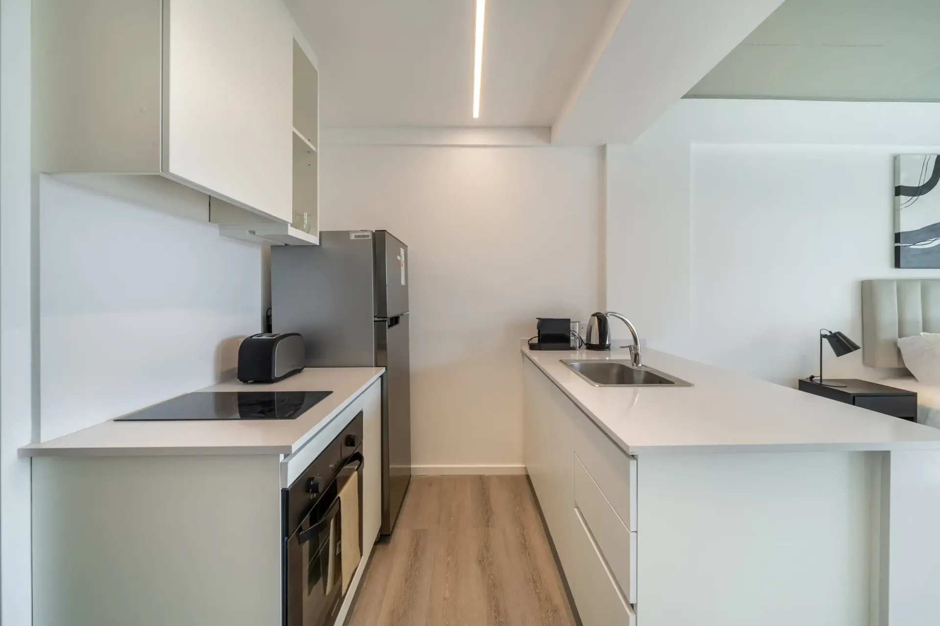 Una cocina con gabinetes blancos, un horno, un refrigerador y un fregadero.