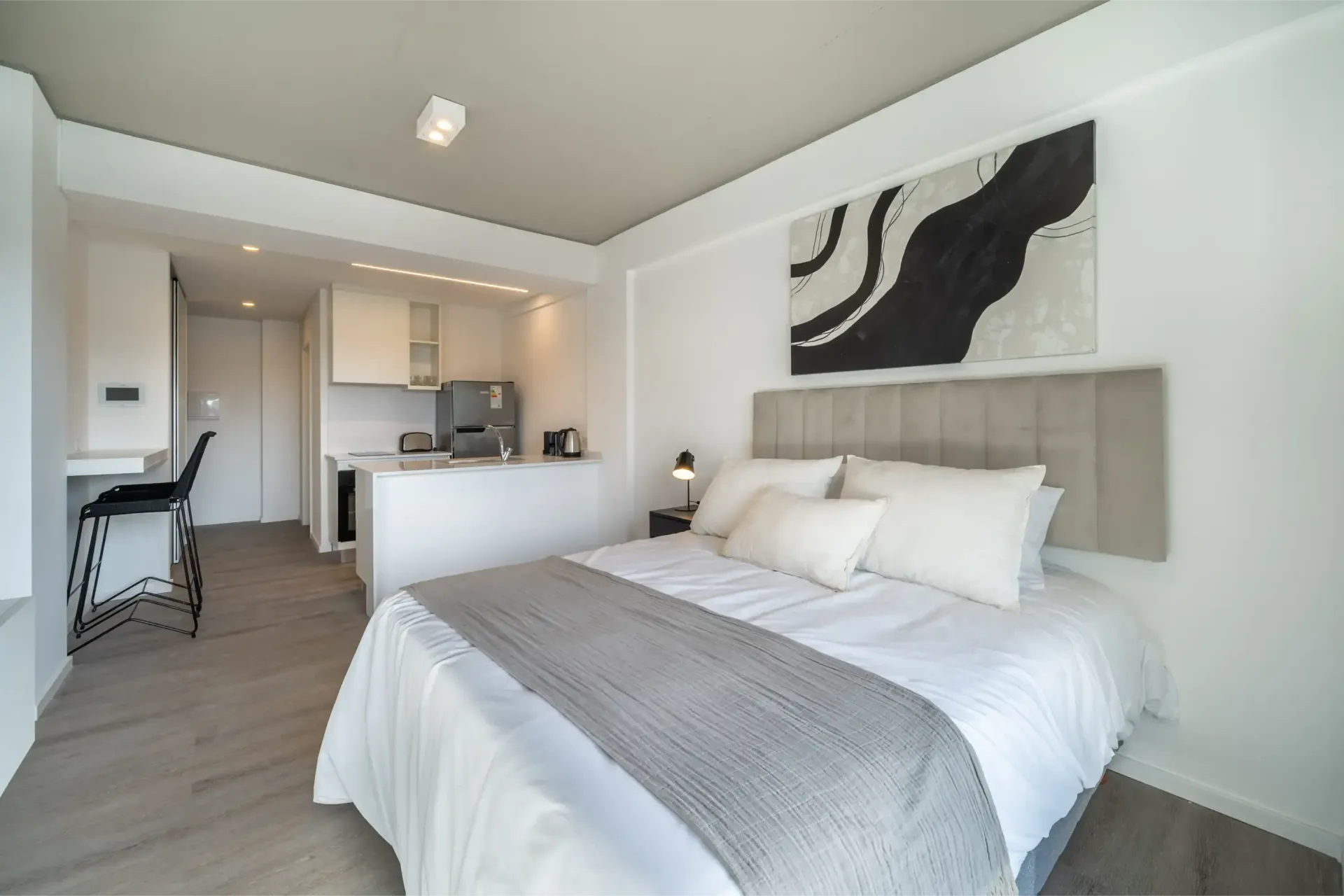 Un dormitorio con una cama grande y una cocina al fondo.