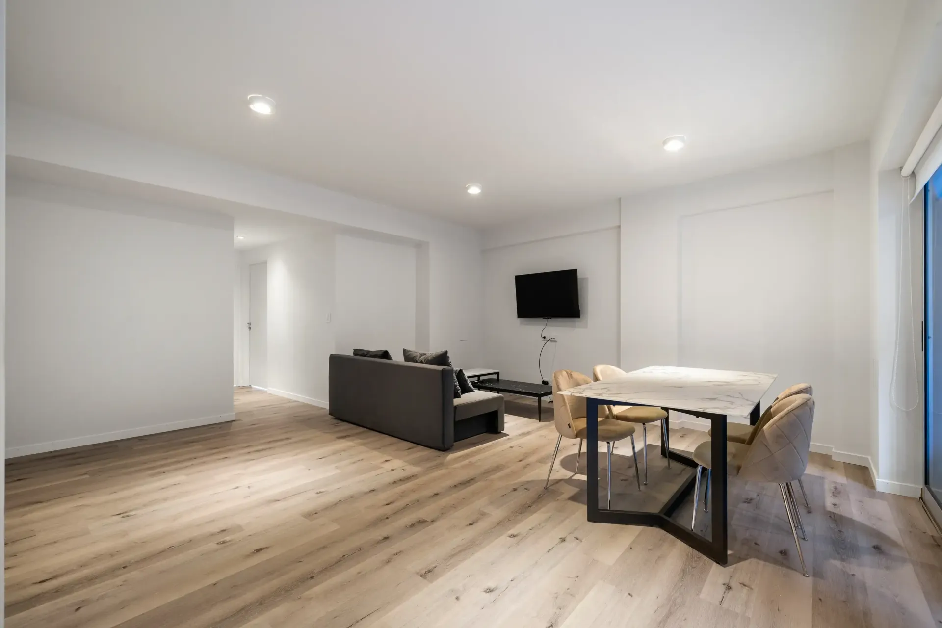 Una sala de estar con un sofá, una mesa, sillas y una televisión.