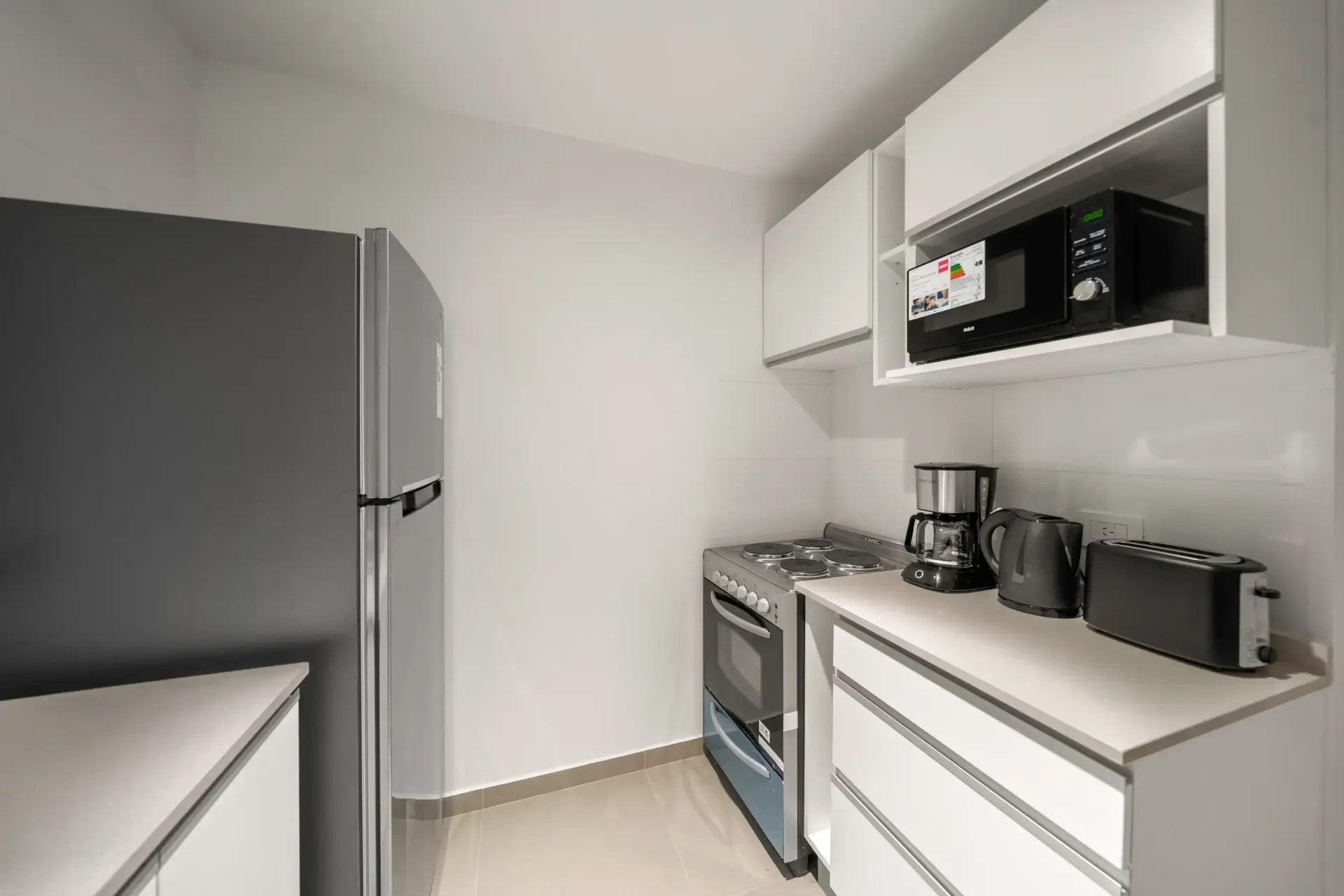 Una cocina con refrigerador, estufa y microondas.