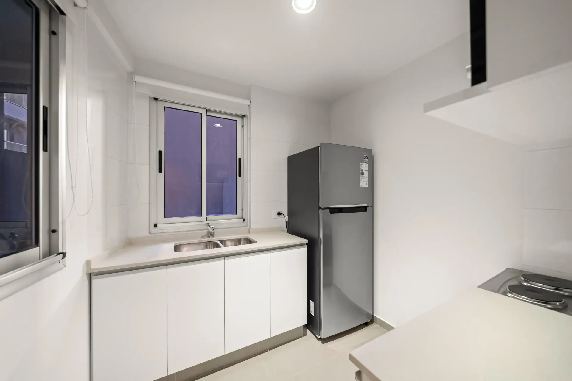 Una cocina con refrigerador, fregadero, estufa y ventana.