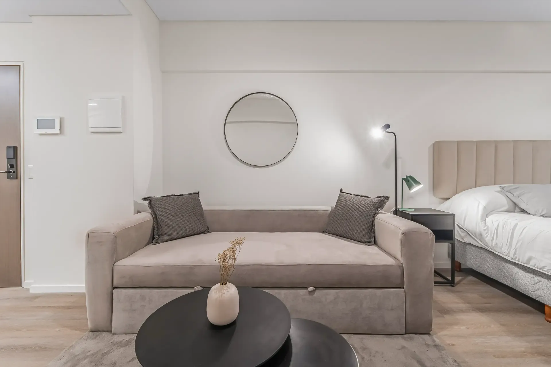 Una sala de estar con sofá, mesa, espejo y cama.
