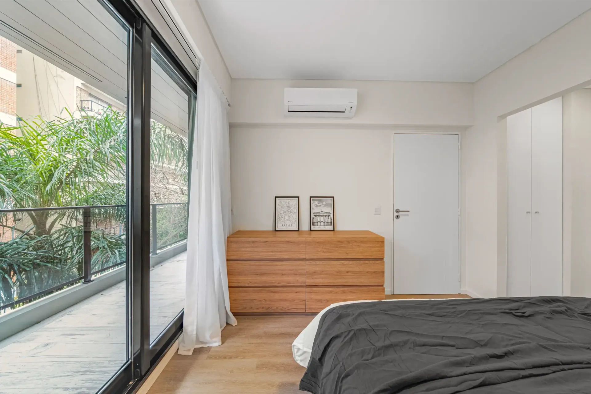 Un dormitorio con cama, tocador y puertas corredizas de vidrio.