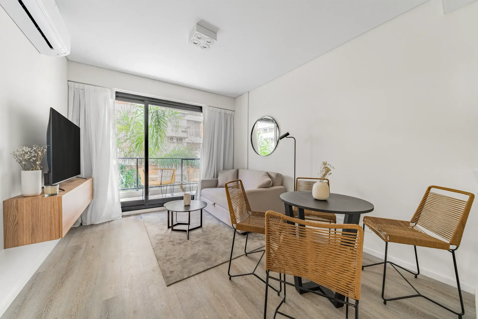 Una sala de estar con un sofá, una mesa, sillas y una televisión.