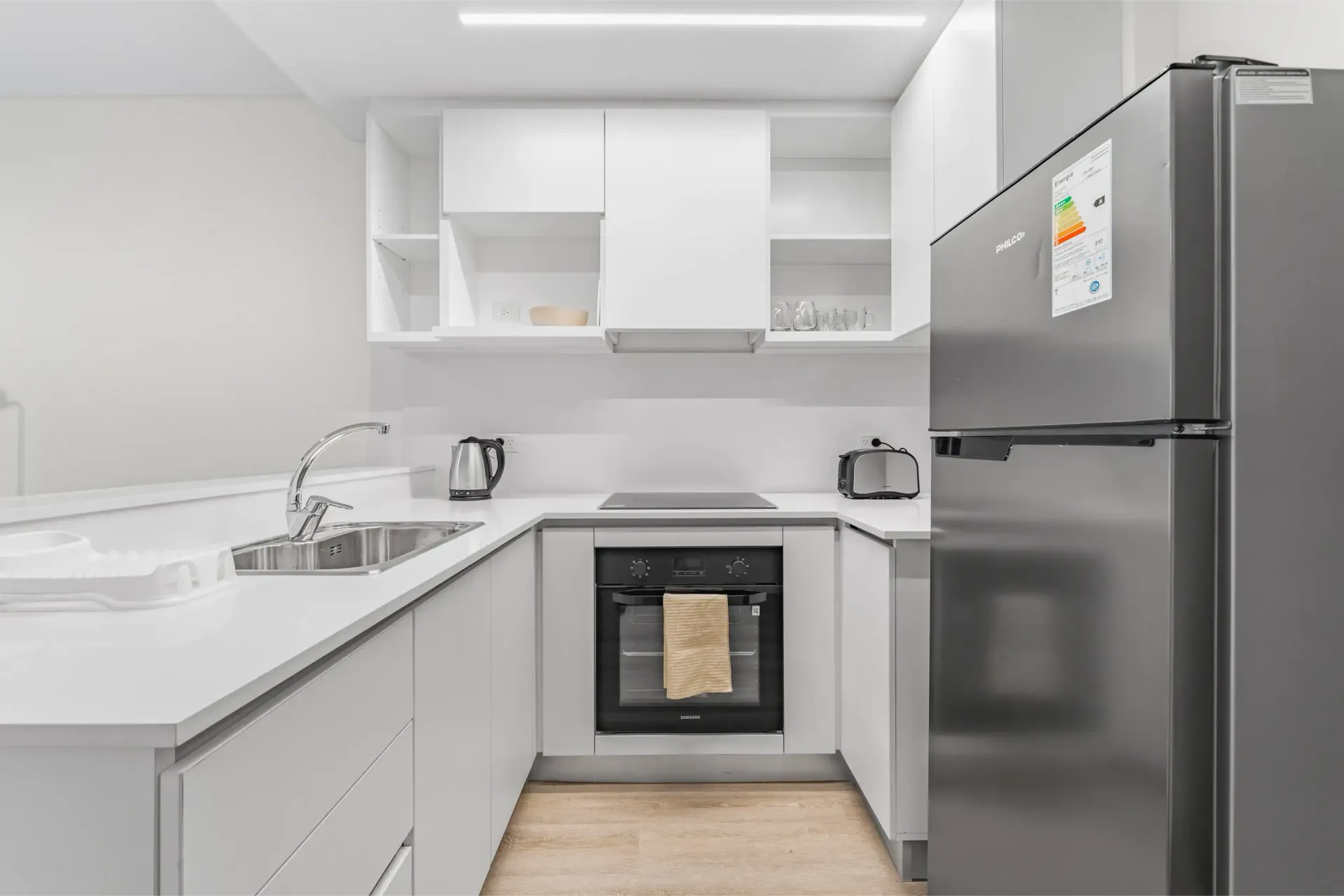 Una cocina con electrodomésticos de acero inoxidable y gabinetes blancos.