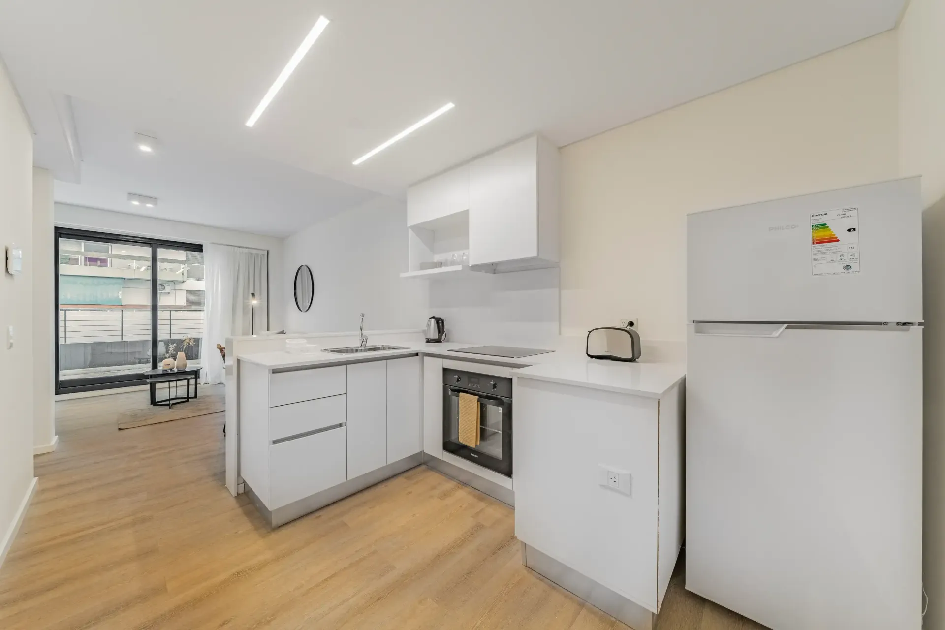 Una cocina con gabinetes blancos, un refrigerador y un horno tostador.