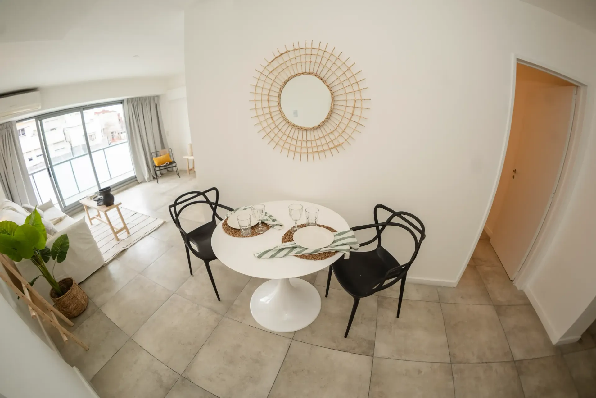 Una sala de estar con una mesa y sillas y un espejo en la pared.