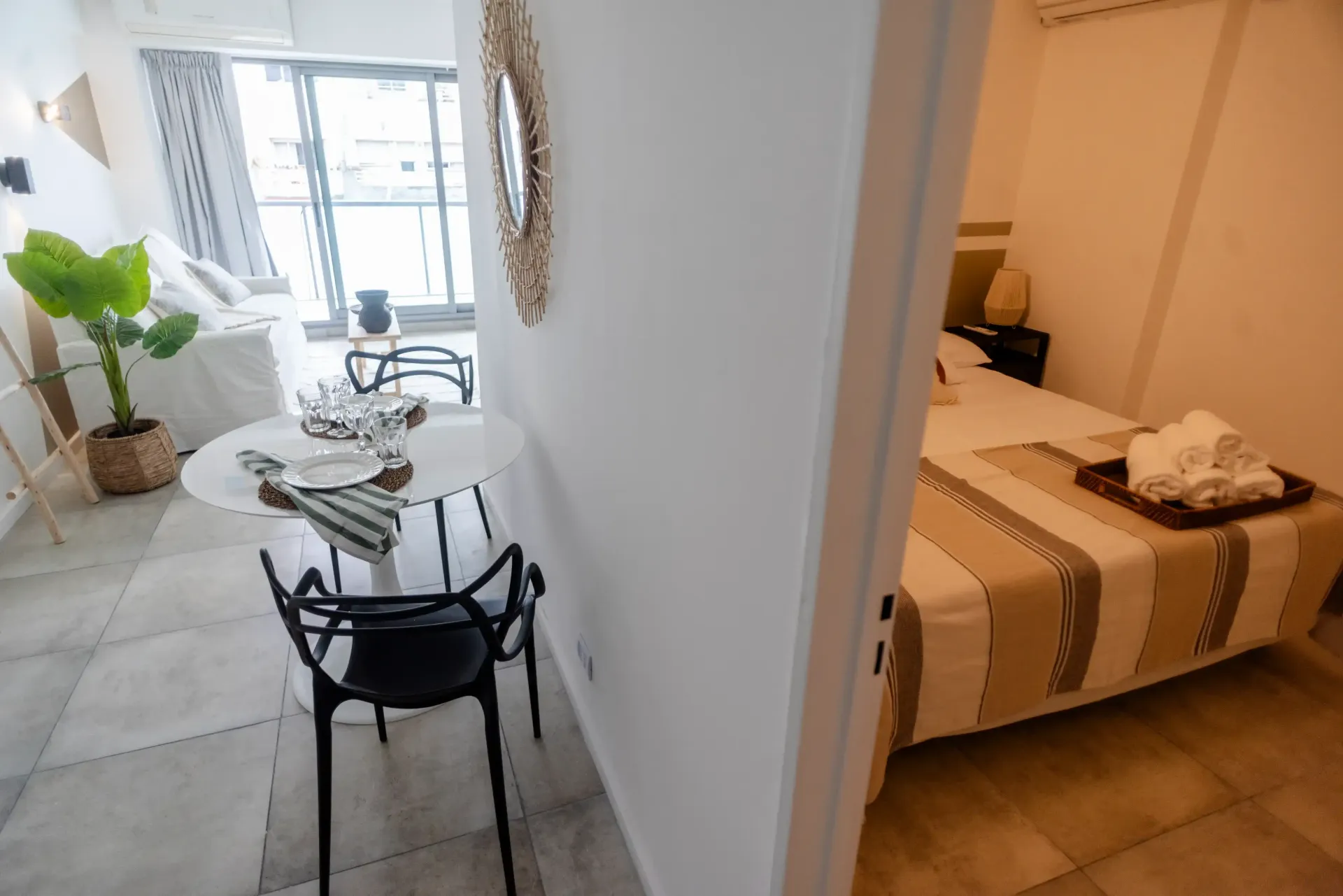 Una sala de estar con una mesa y sillas y un dormitorio con una cama.