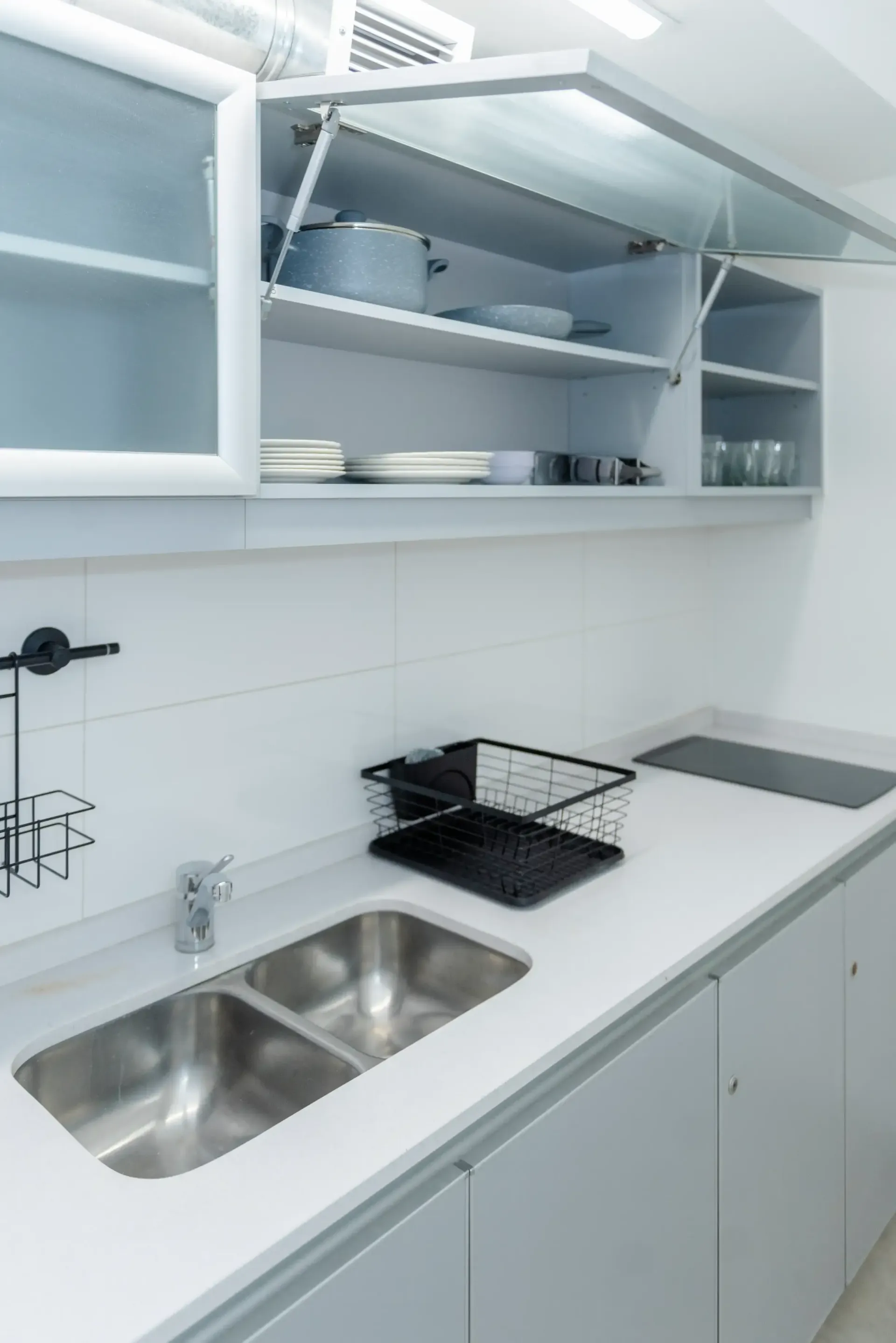 Una cocina con fregadero, estufa y estantes abiertos.