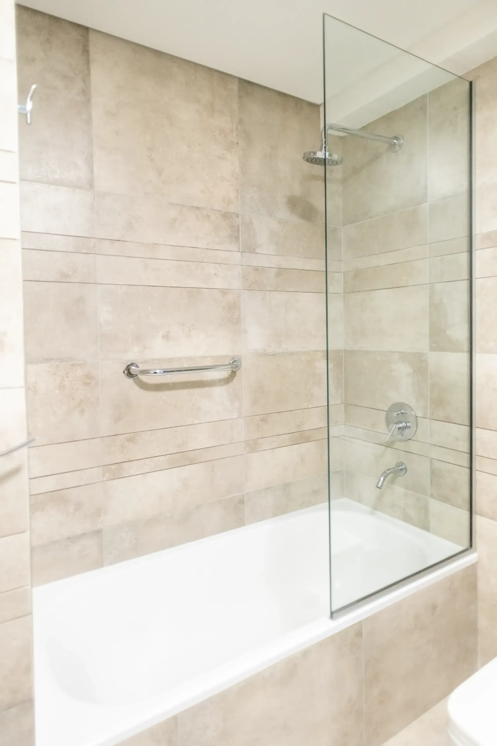 Un baño con bañera y ducha con puerta de cristal.