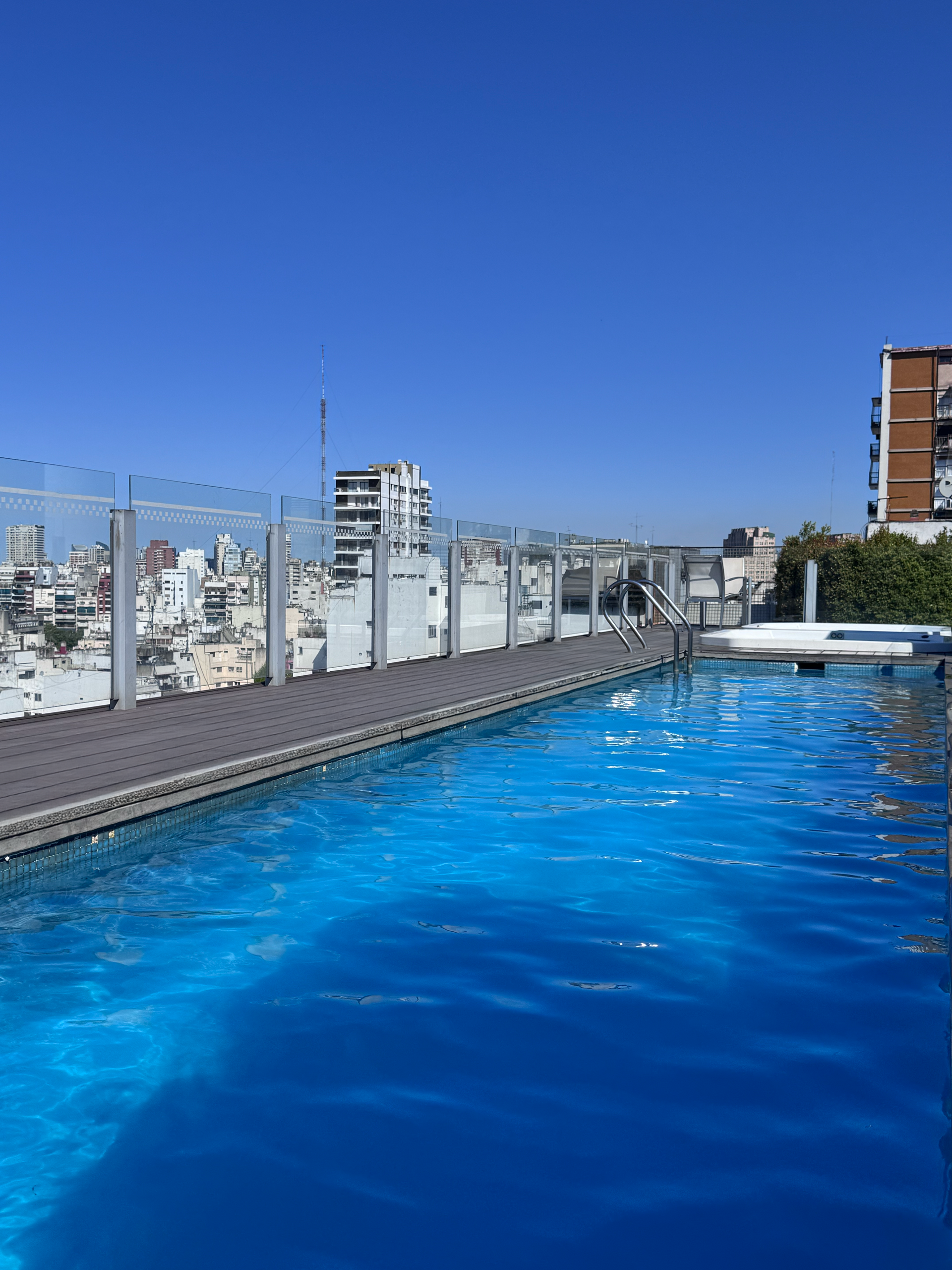 Una piscina en la azotea de un edificio con una ciudad al fondo.