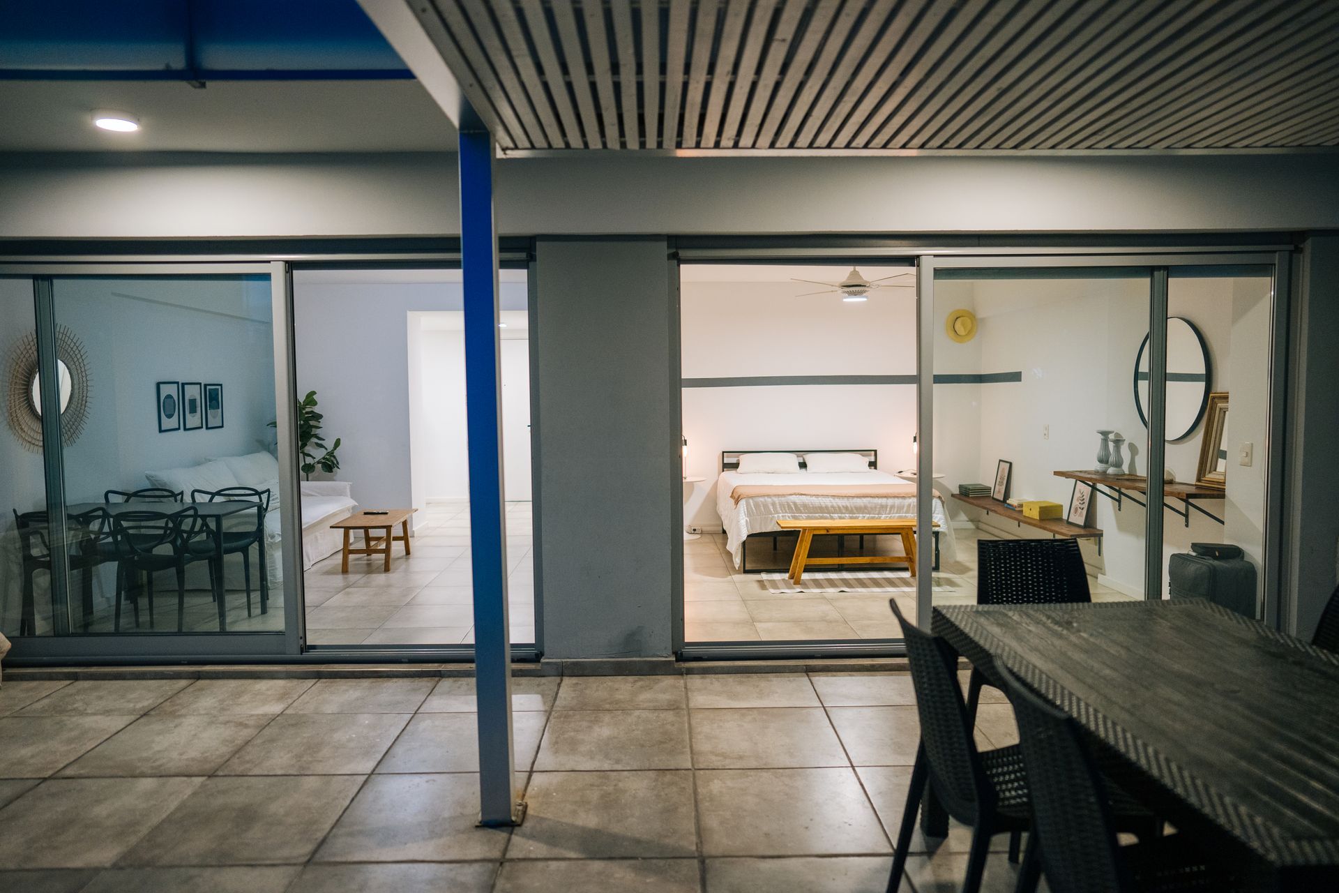 Un patio con una mesa de comedor de madera se abre, a través de grandes puertas corredizas de vidrio, a un luminoso dormitorio y a una sala de estar independiente.