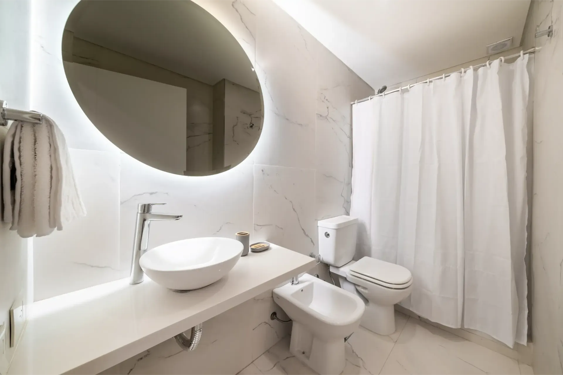 Un baño con lavabo, inodoro, bidé y cortina de ducha.