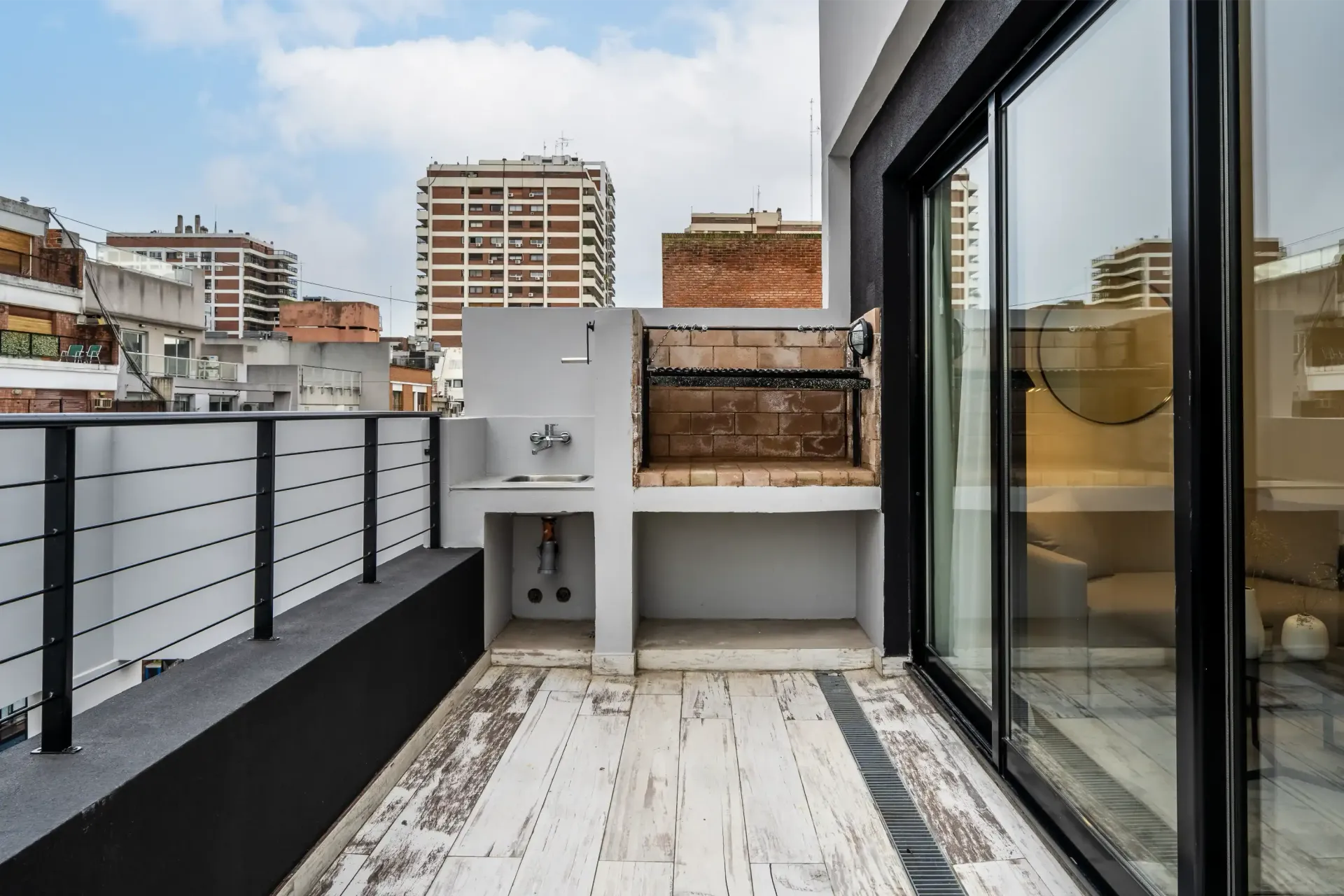 Un balcón con parrilla y puertas corredizas de vidrio.