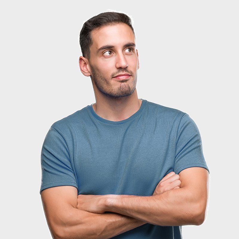 Man in a blue T-shirt with arms crossed, looking to the side against a white background
